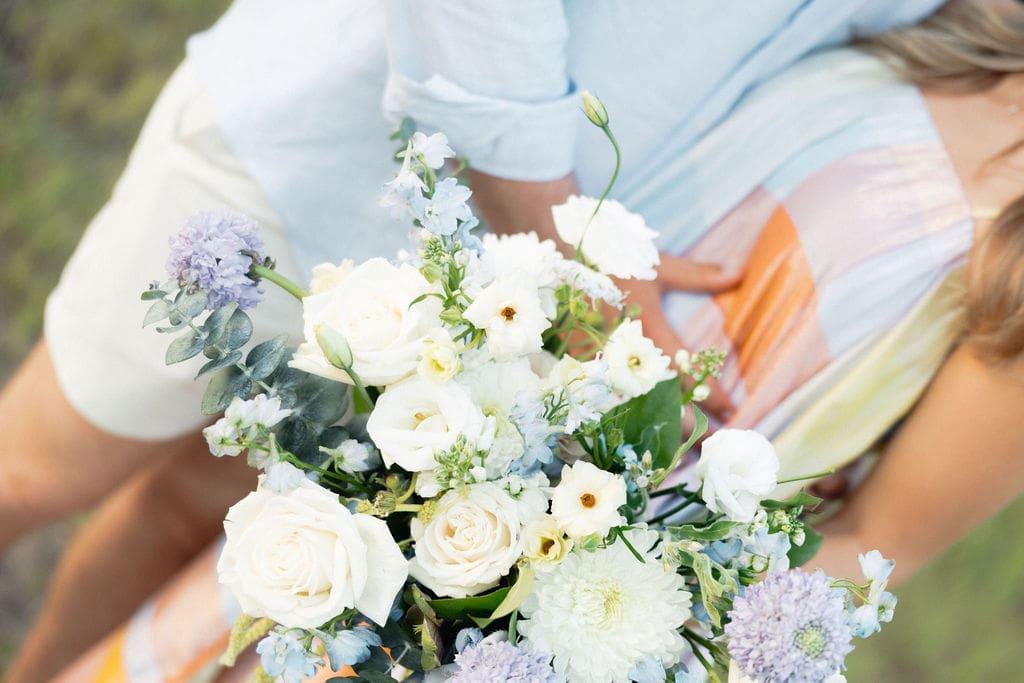 A closeup of the couple huggin onto each other while holding their gender reveal floral bouquet.