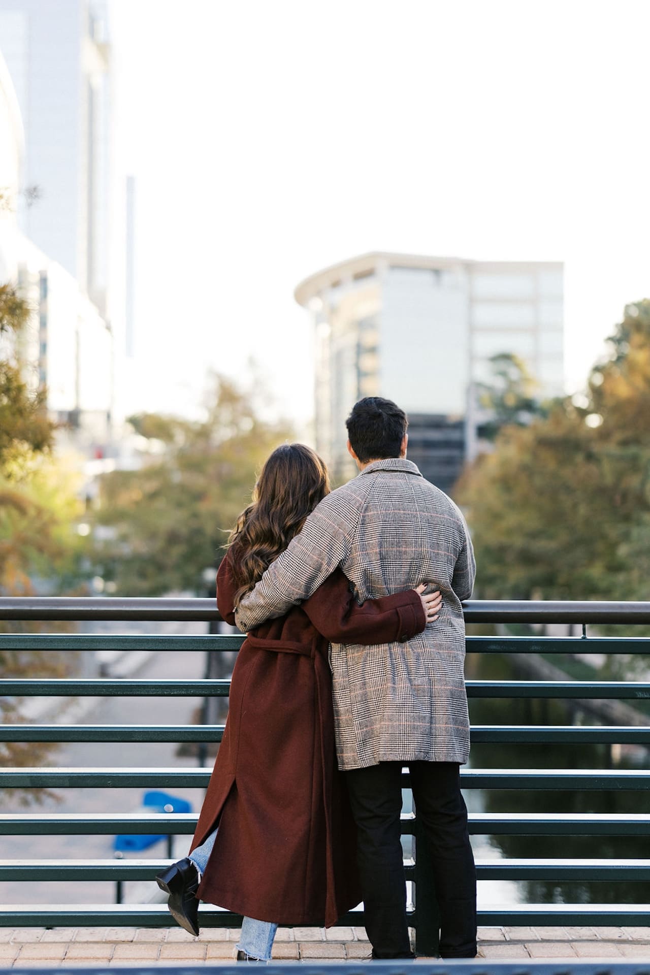 Couple standing with their backs to the camera in front of a railing.