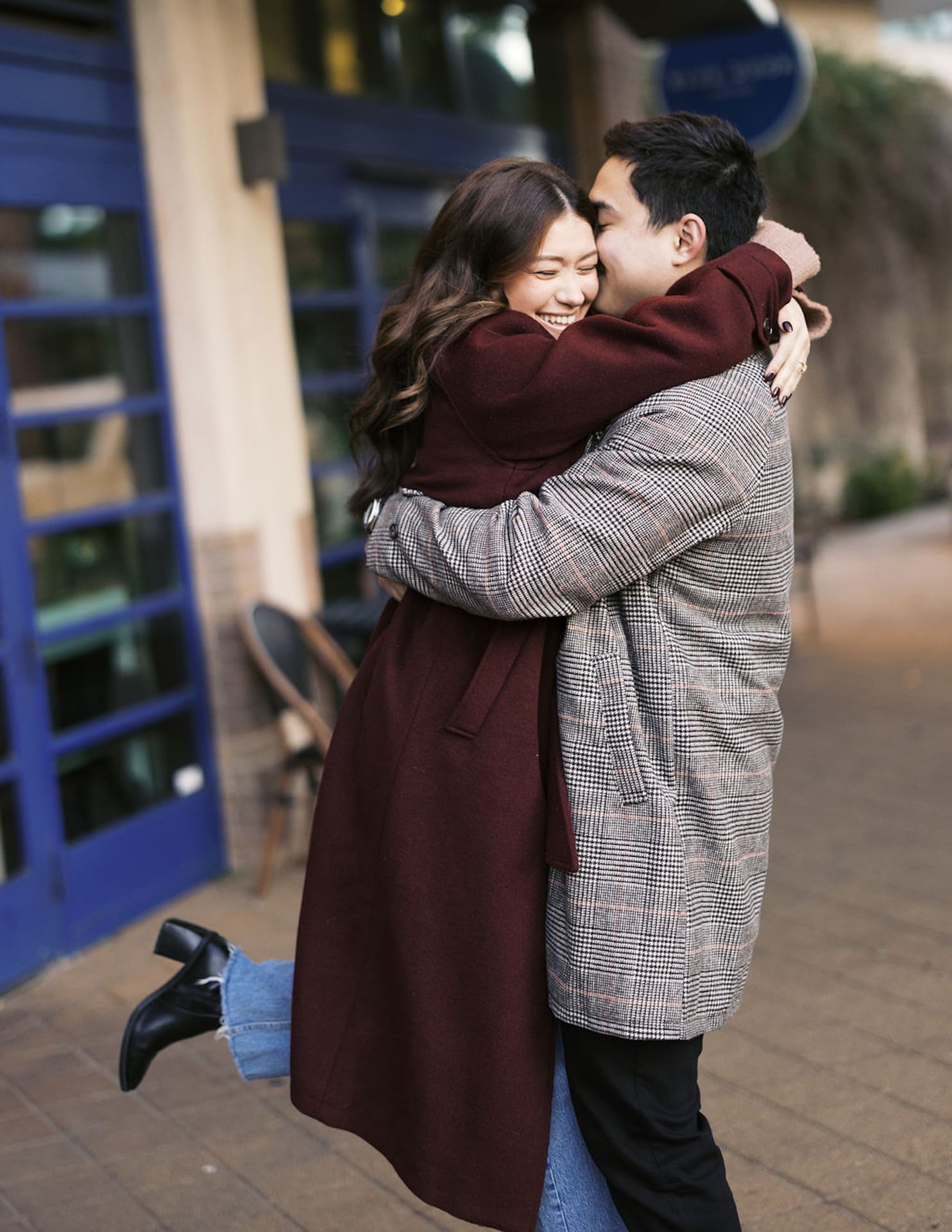Couple twirling on the sidewalk with the girl laughing and holding onto her fiance.