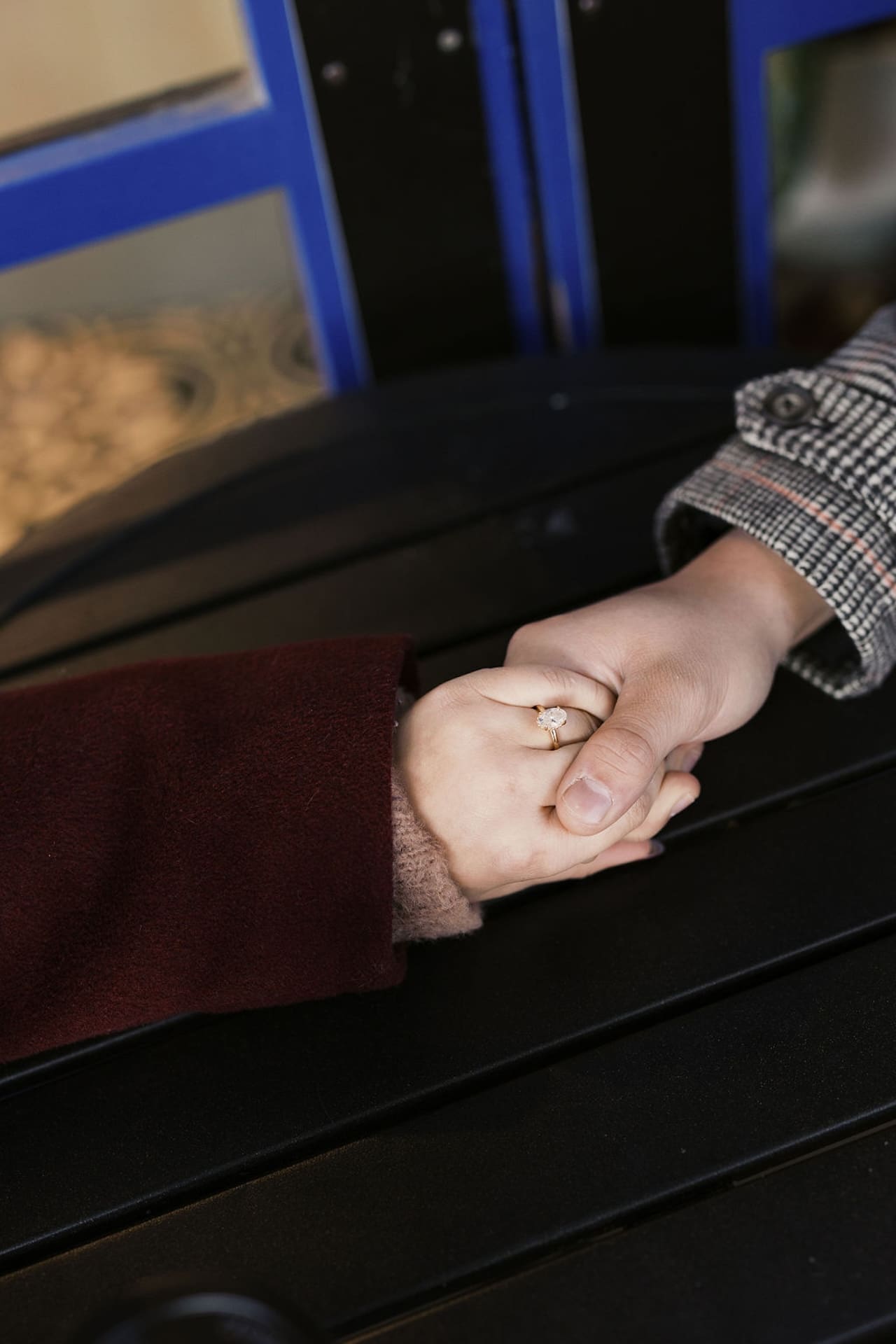 A detail photo of the engaged couple holding hands over a table outside during their engagement shoot. 