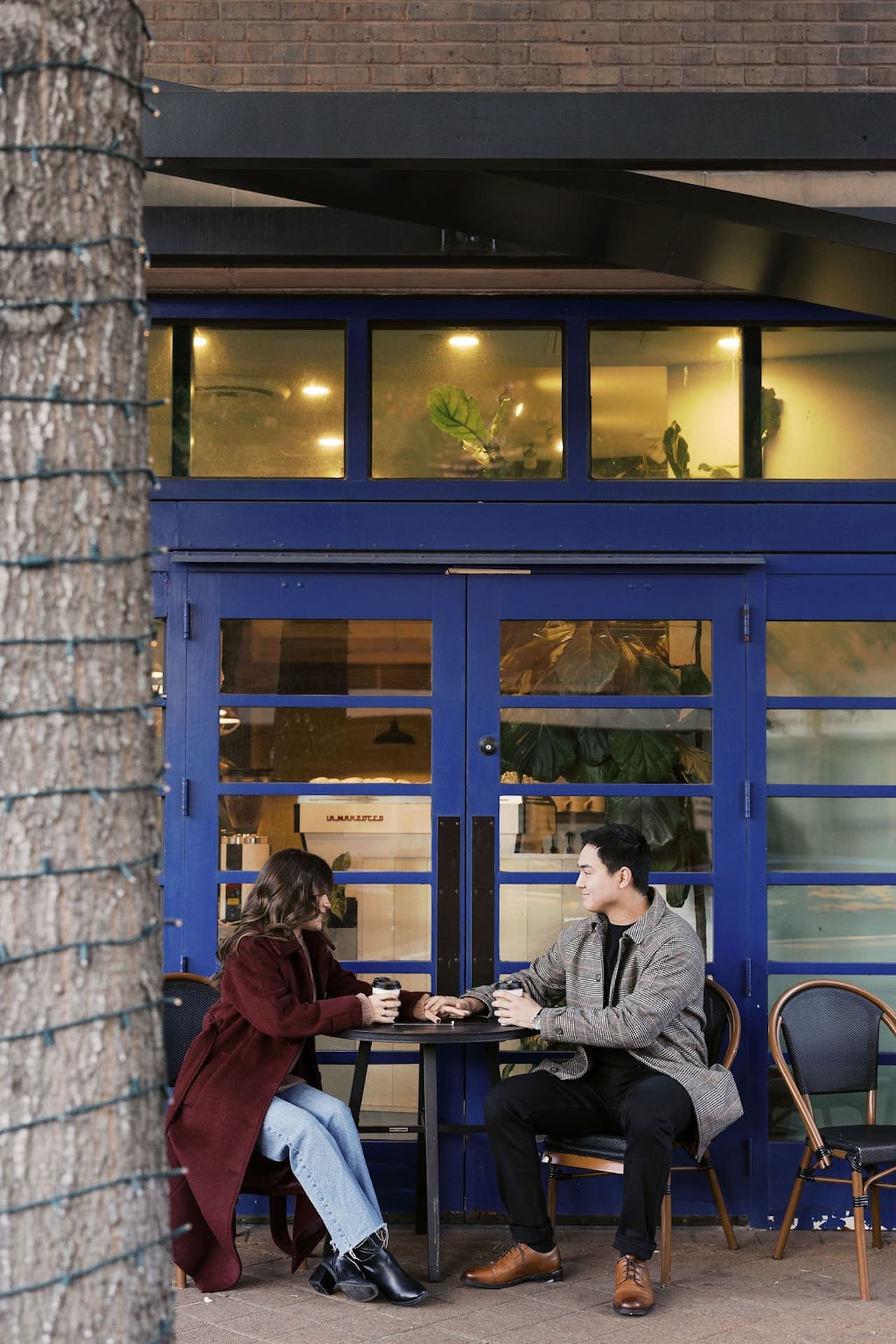 Couple sitting at a table outside of a coffee shop in The Woodlands of Texas during their morning engagement shoot.