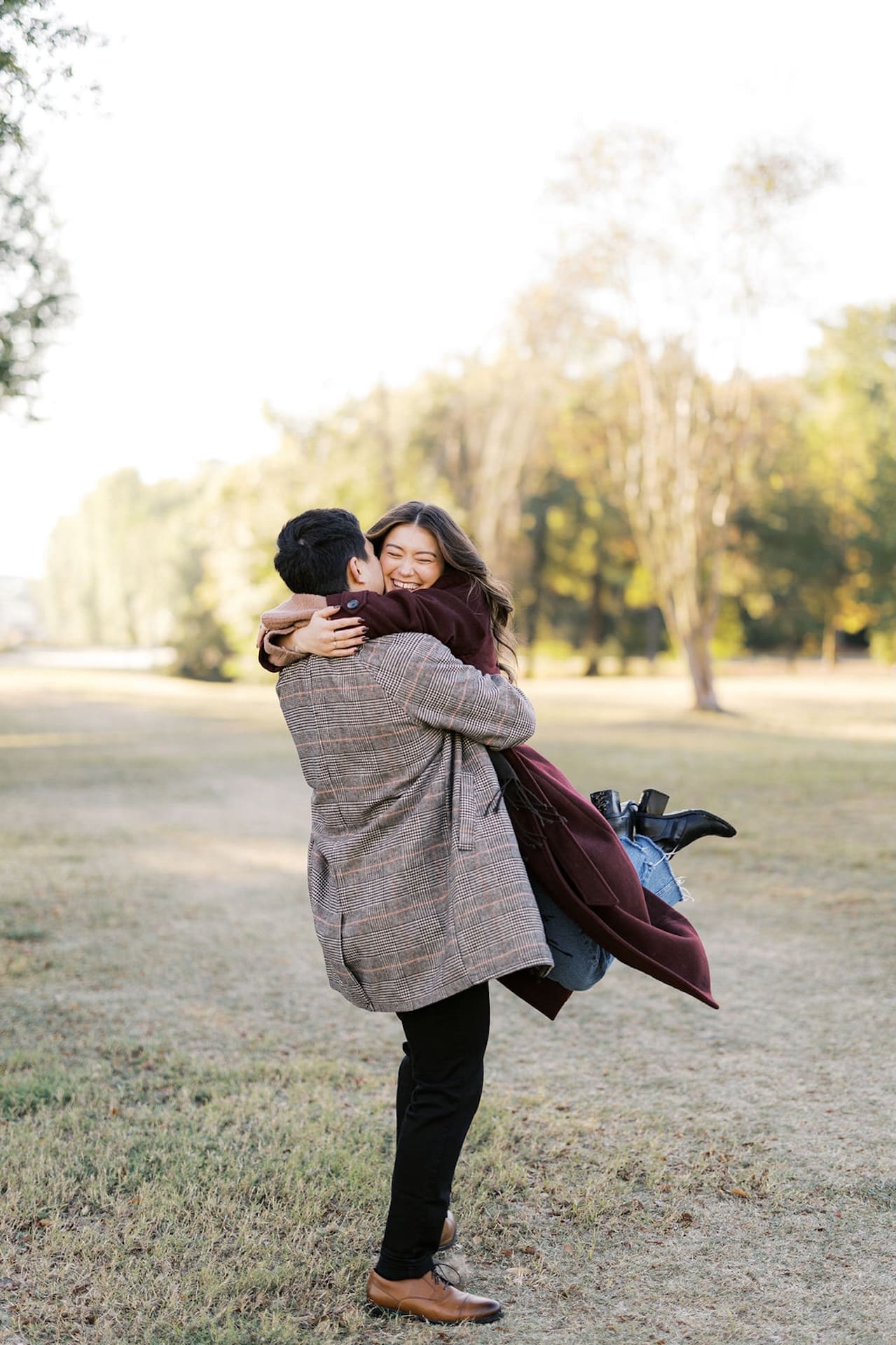 Man twirling his fiance as she hugs onto him and laughs during their chilly sunrise engagement shoot.