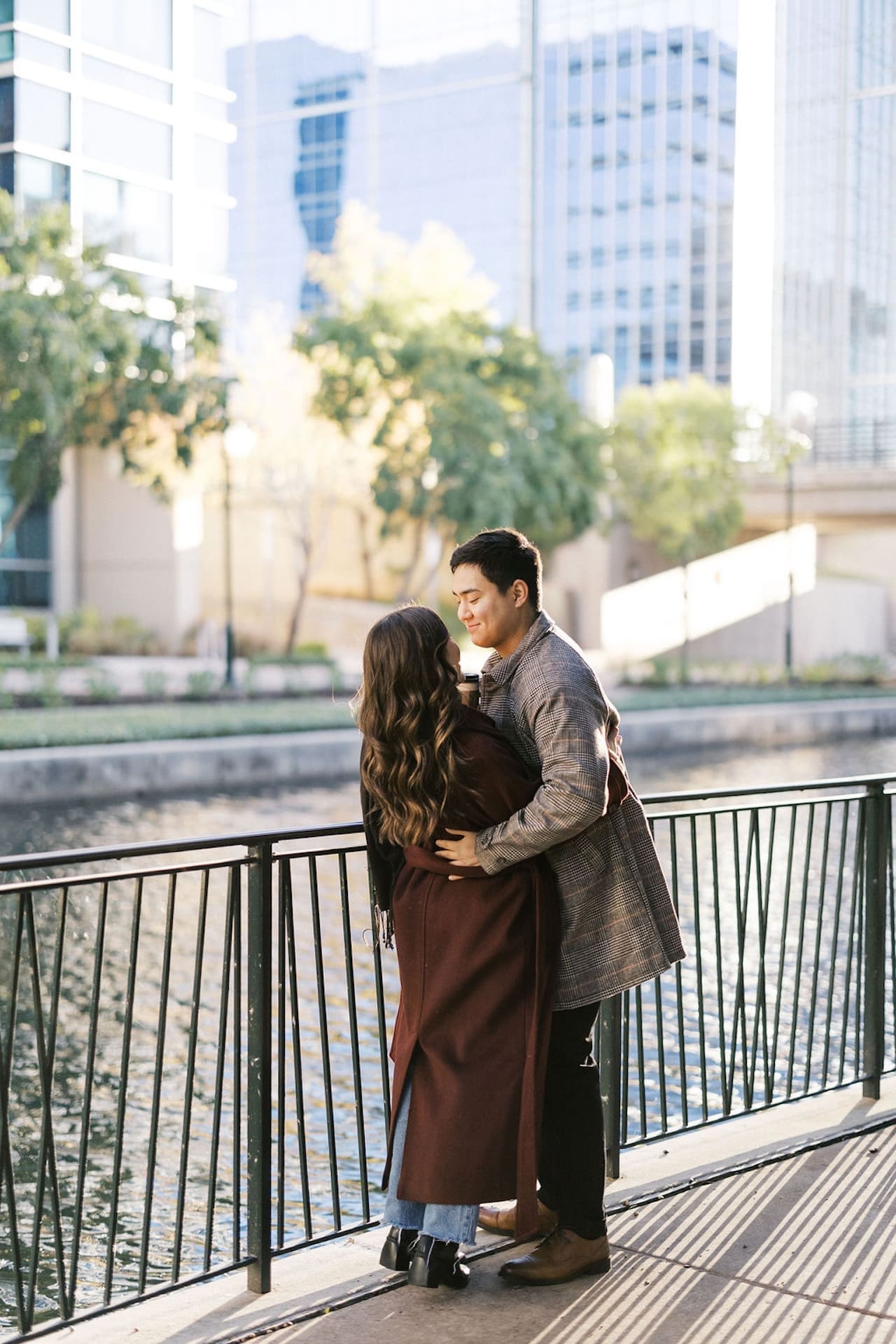 Engaged couple standing by a railing along the river at The Woodlands in Texas during their sunrise engagement shoot