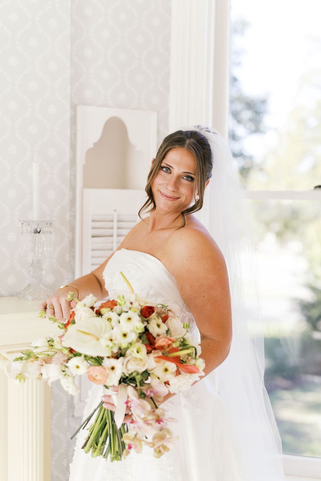 The bride smiling softly at the camera as she holds her elegant wedding bouquet