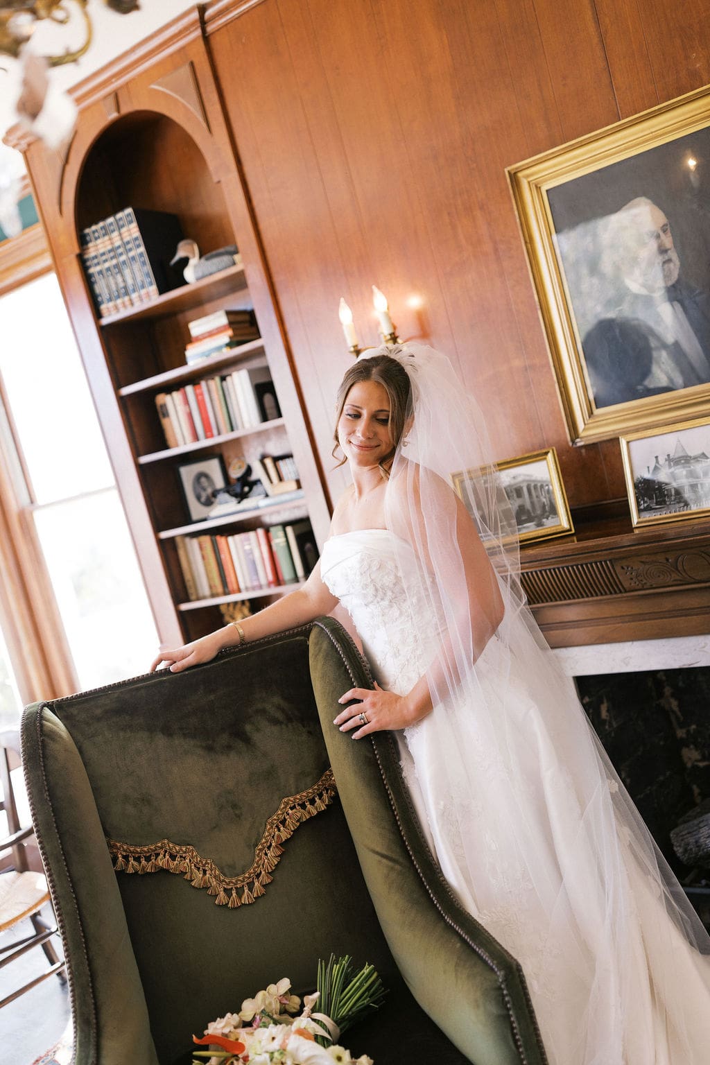 An elegant bridal photo of the bride leaning against a vintage chair at Woodbine Mansion
