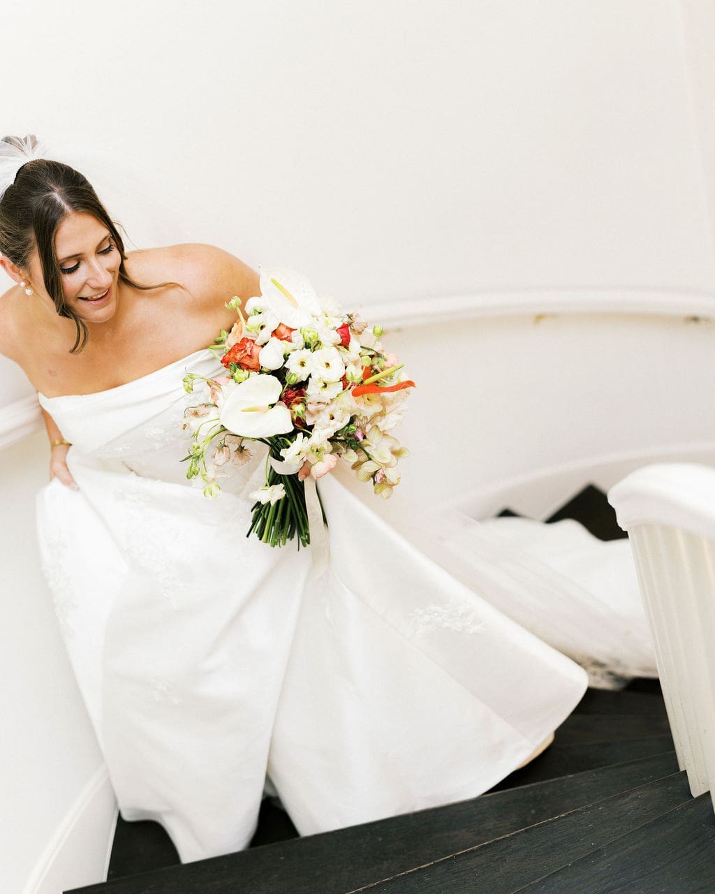 A candid bridal portrait of the bride walking up the staircase at Woodbine Mansion holding her dress and bridal bouquet
