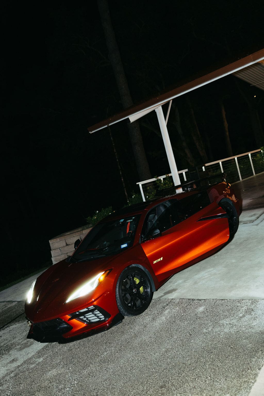 A fun flash photo of the bride and groom leaving their wedding venue in a bright red corvette.