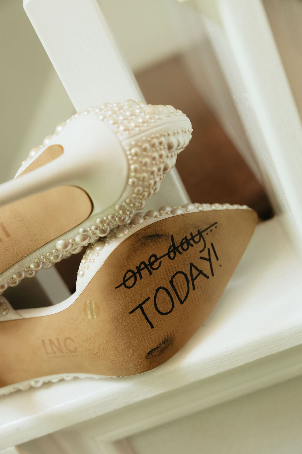 A detail photo of the brides pearl heels, with the words, "One day, Today!" with the words "One Day" crosses out written on the bottom.