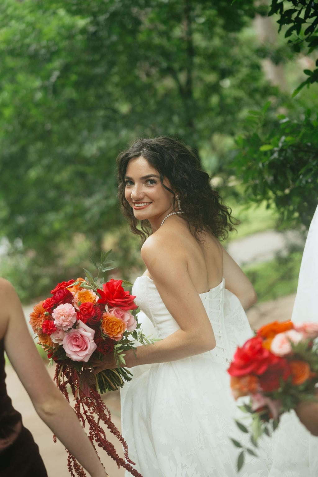 A candid portrait of the bride walking down the walkway with her bridesmaids while she looks back at the camera, a stunning example of documentary wedding photos.