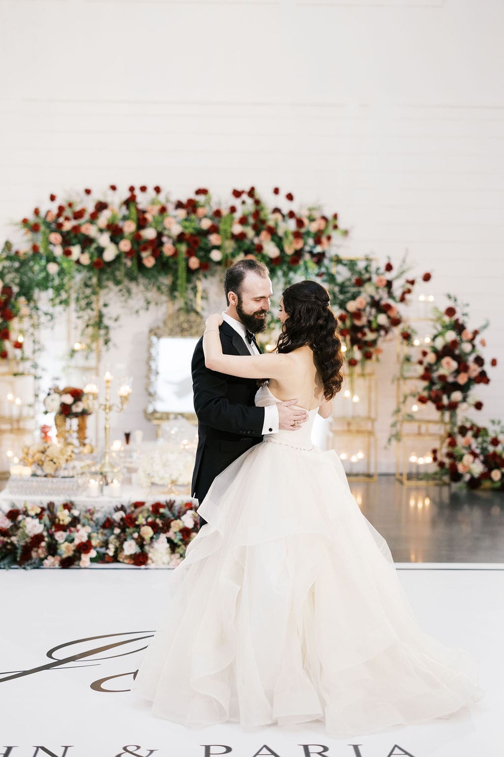 The bride and groom share their first dance in front of the illuminated sofreh aghd backdrop at their Persian wedding at Boxwood Manor Houston.