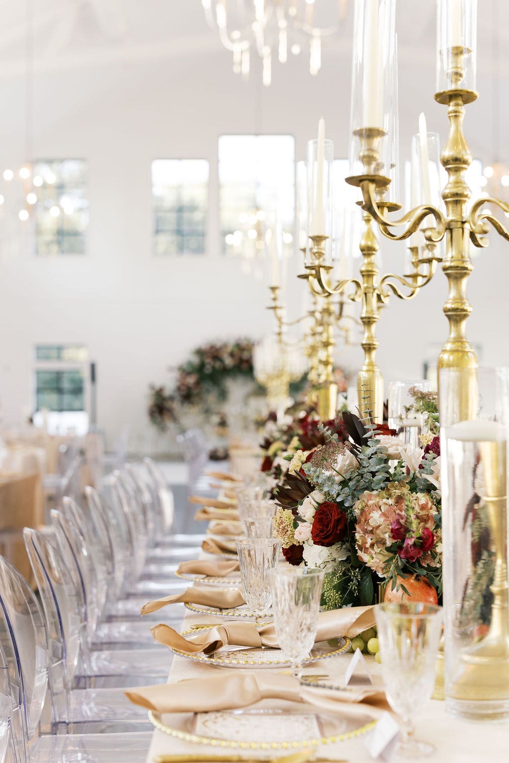An elegant reception table runner with tall gold candelabras, lush floral centerpieces, and champagne satin napkins at Boxwood Manor.