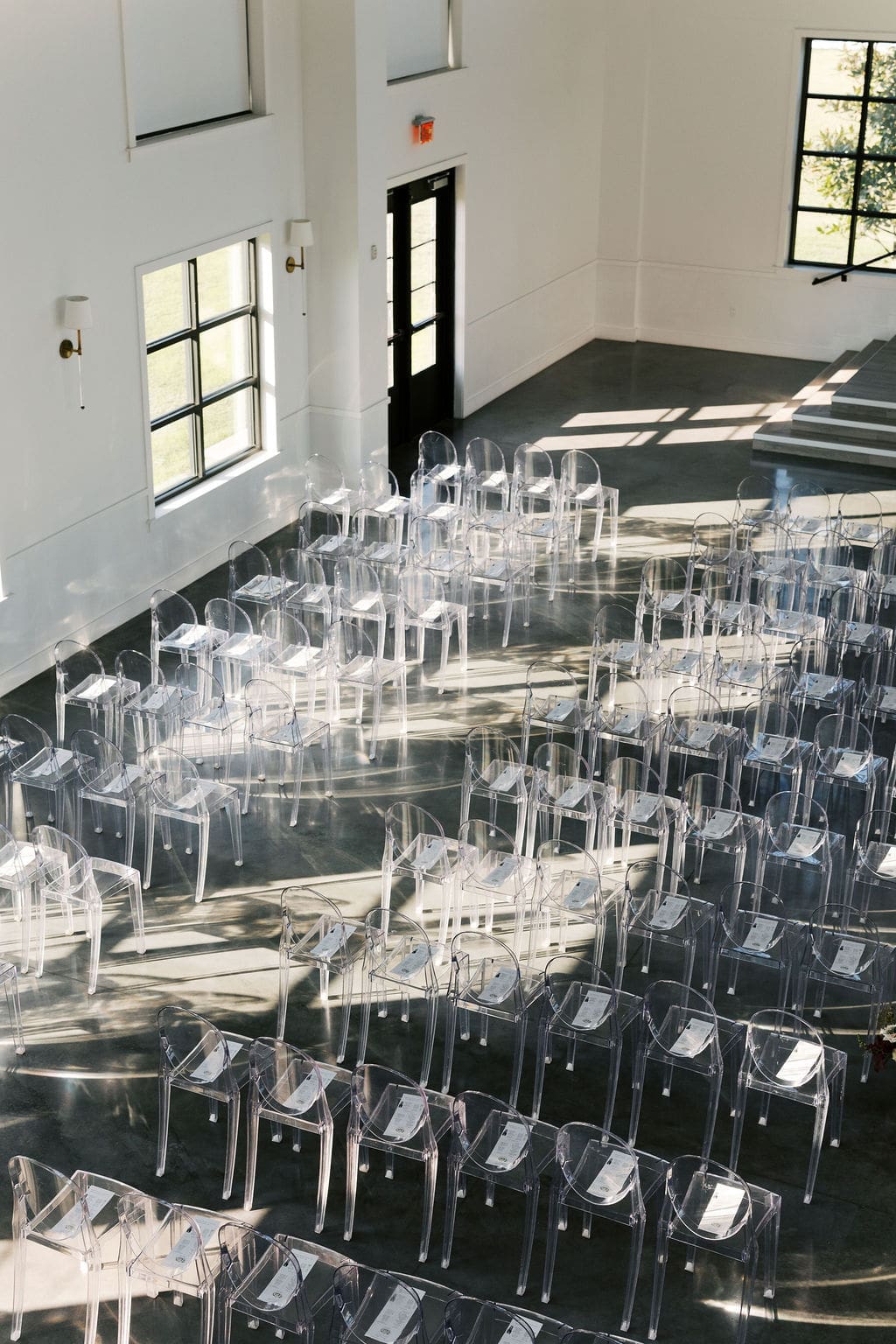 Rows of empty chairs arranged in a sunlit ceremony space with polished concrete floors at Boxwood Manor Houston.