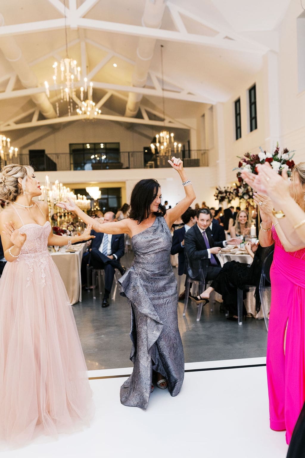 Guests celebrate on the dance floor during the lively Persian wedding reception under crystal chandeliers at Boxwood Manor Houston.