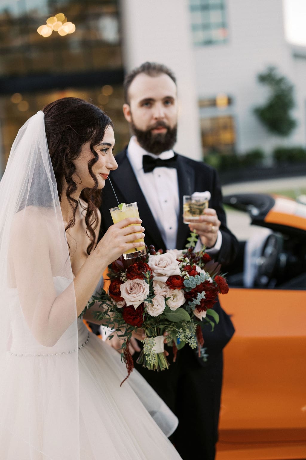 The newlyweds share a kiss inside a flower-adorned orange sports car as they make their grand exit into the night.