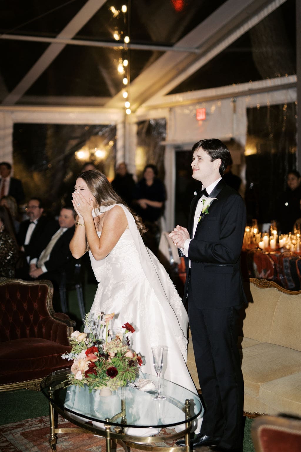 Bride reacting emotionally during a heartfelt reception moment inside a candlelit tent at a Mansion Wedding reception.