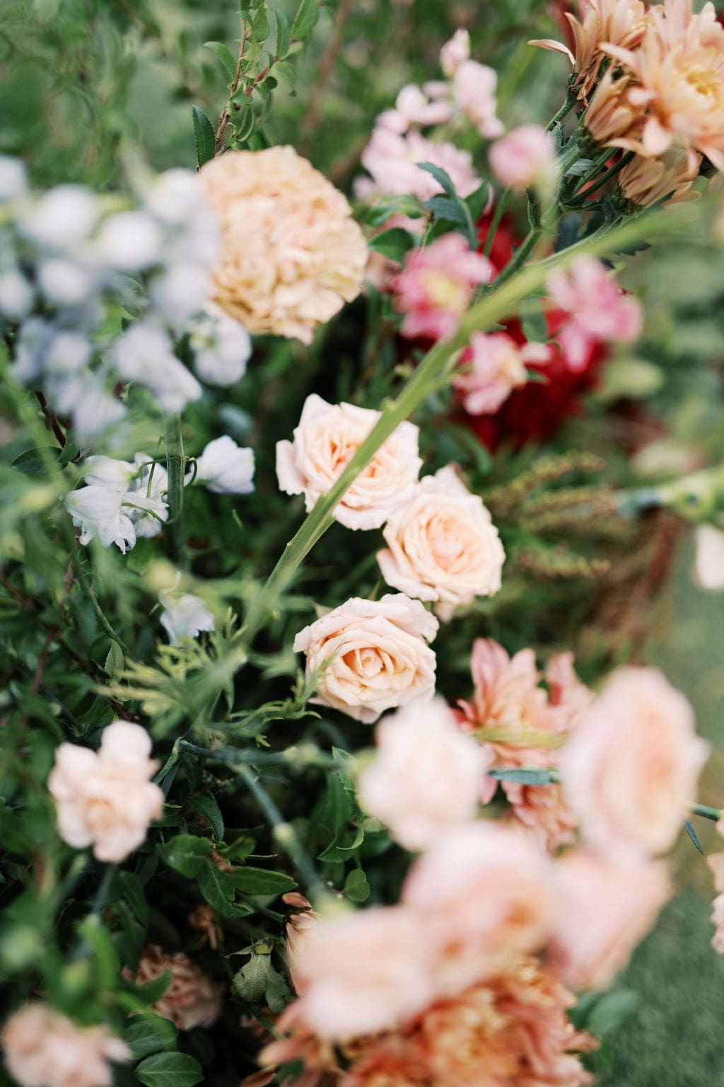 Close-up of romantic garden florals with peach roses and greenery decorating the ceremony space at a Mansion Wedding.