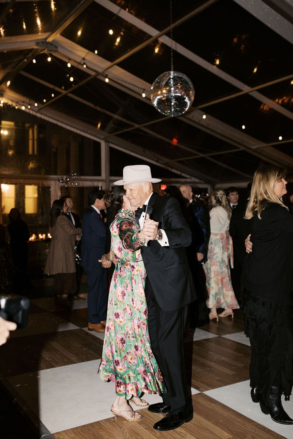 Guests dancing together beneath a disco ball on the dance floor during a festive Mansion Wedding reception.