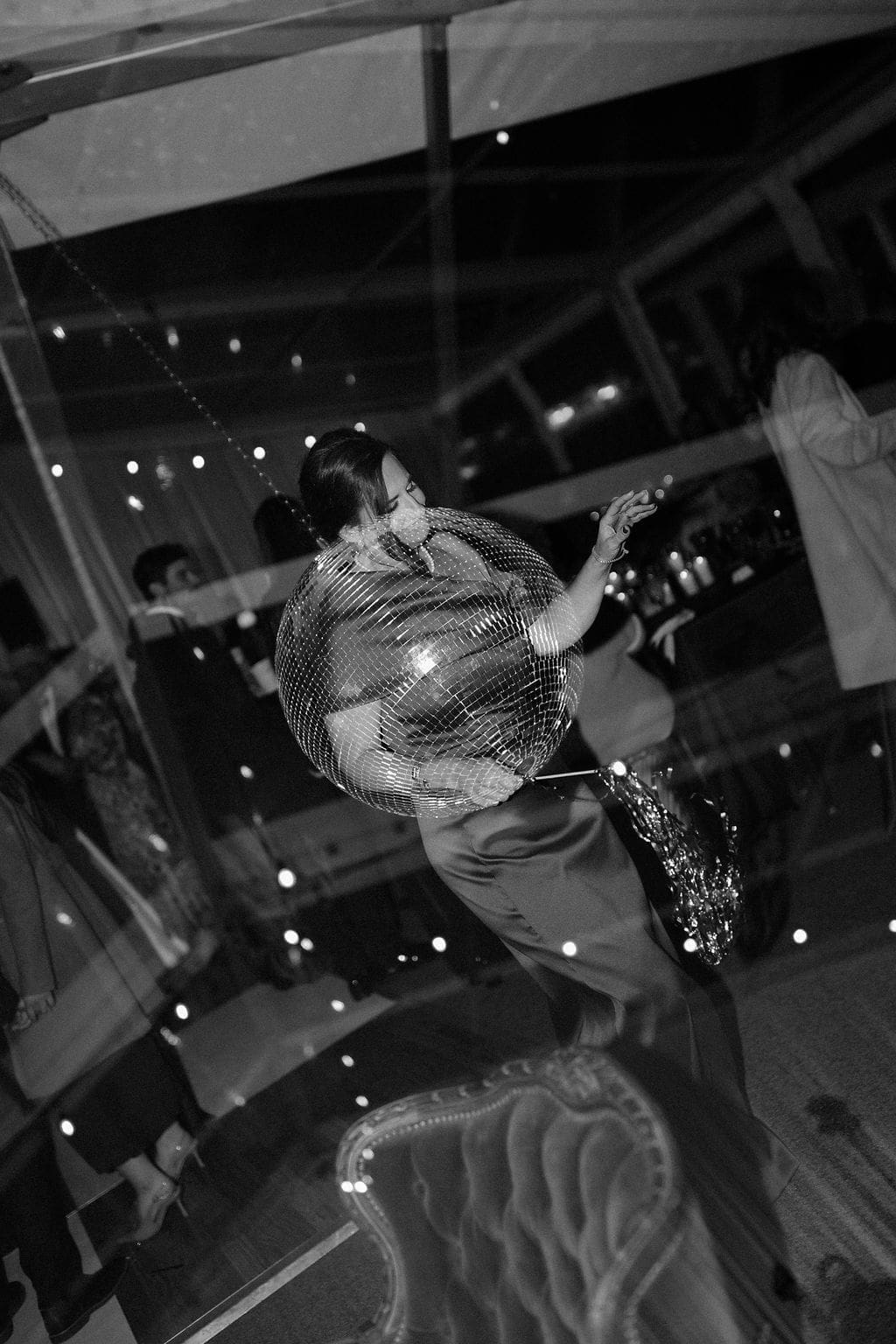 Stylish guest dancing with a disco ball prop during a lively evening reception at a Mansion Wedding celebration.
