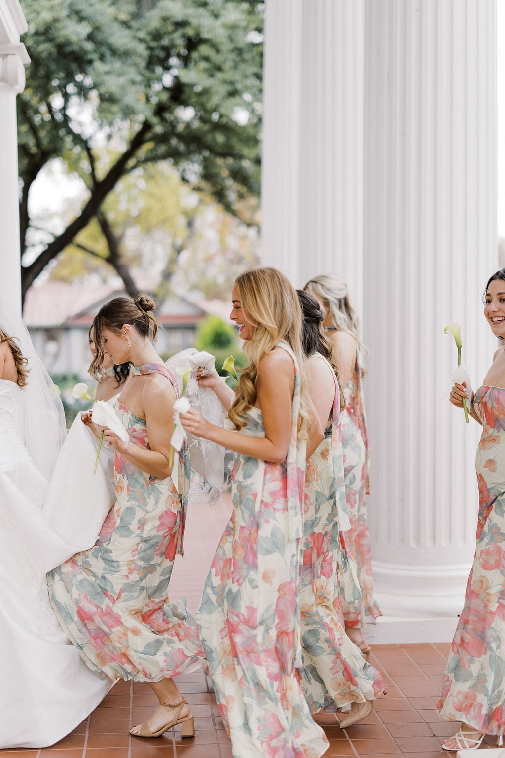 Bridesmaids walking with the bride beneath grand white columns at a classic Southern Mansion Wedding venue.