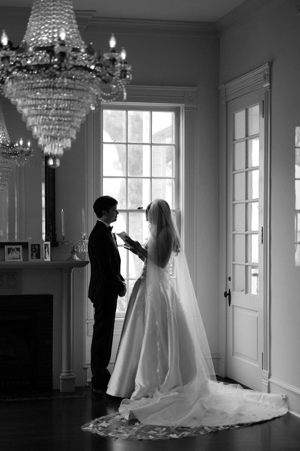 Black-and-white portrait of a bride reading vows to her groom inside an elegant room during a Mansion Wedding.