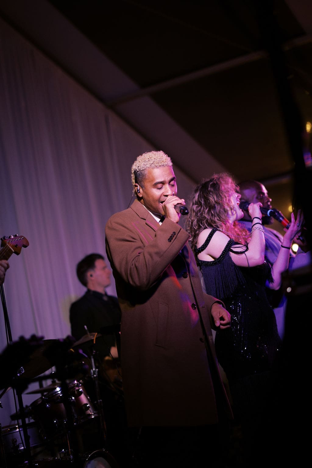 Live band performing on stage with vibrant lighting during a high-energy Mansion Wedding reception.