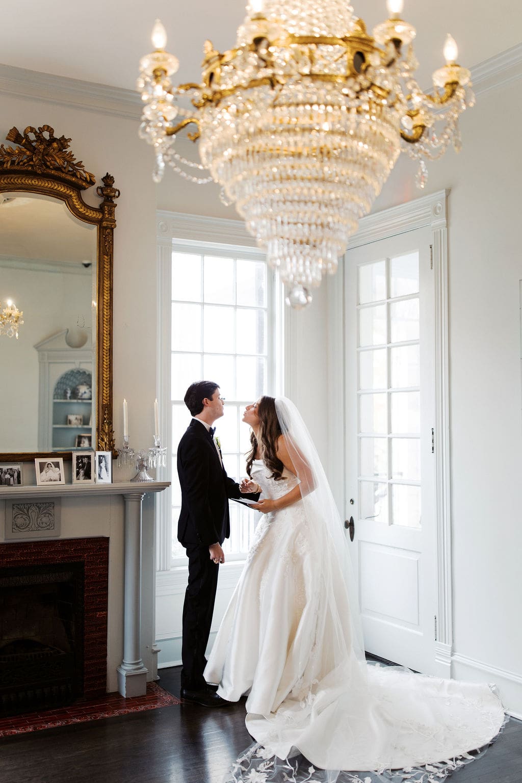 Bride and groom sharing a quiet moment beneath a crystal chandelier during an elegant Mansion Wedding portrait inside a historic estate.
