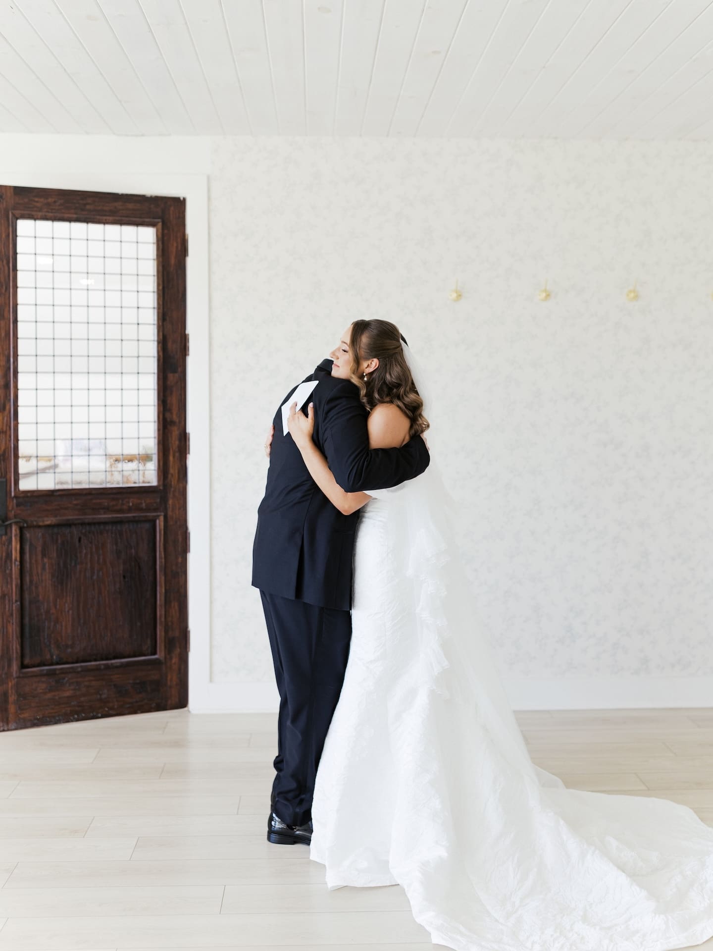 The bride and her dad share a long, emotional hug during their first look, her cathedral train pooling around them on the floor.
