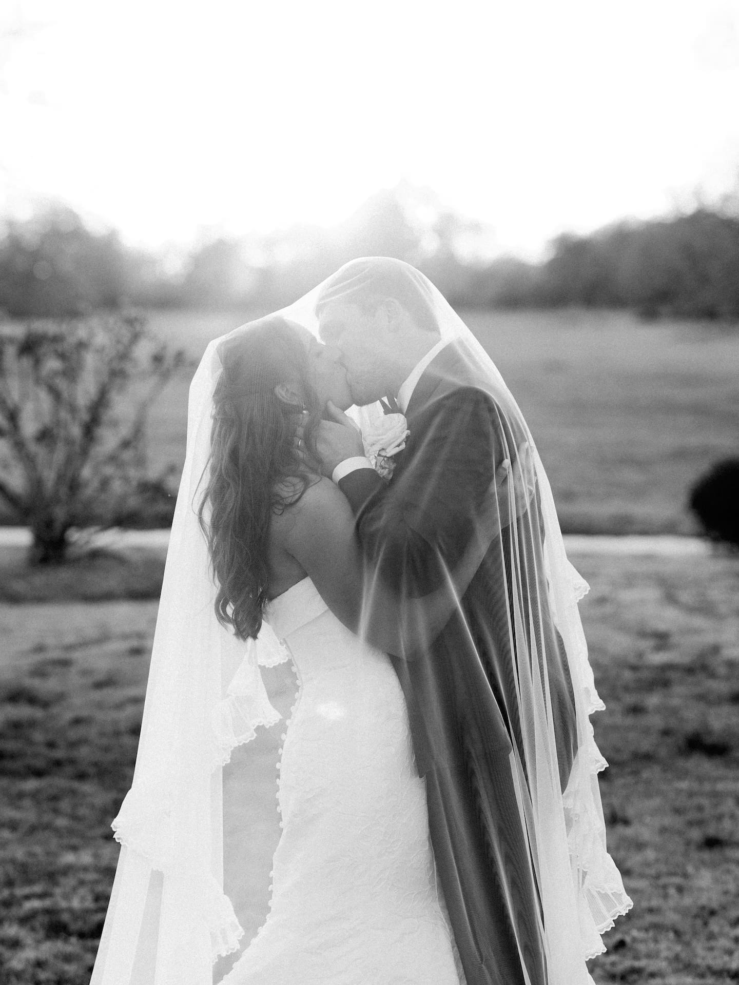 The bride and groom share a tender kiss beneath her cathedral veil at Camp Hosea, wrapped in the warm glow of golden hour.