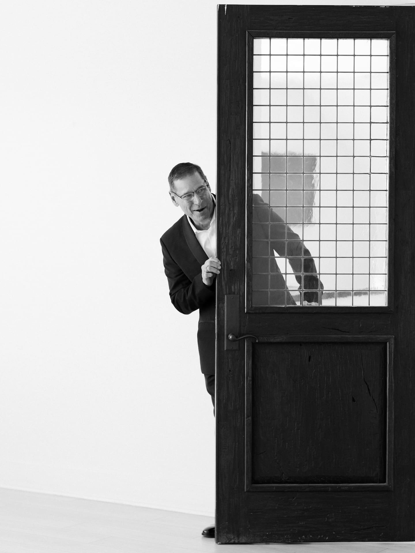 A playful black and white shot of the father of the bride peeking around the chapel door with a big grin.