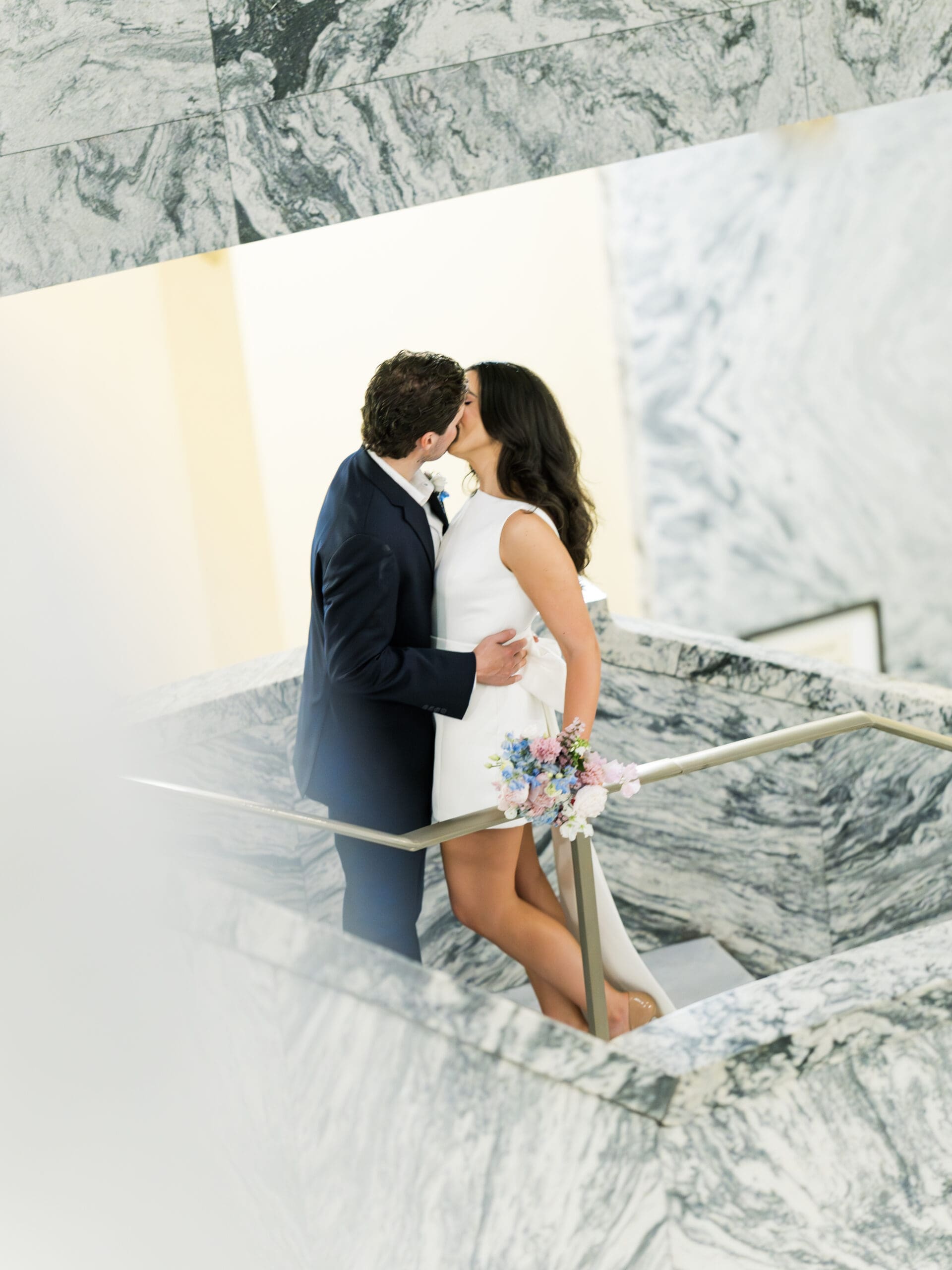 Couple sharing a kiss on the marble staircase inside the Harris County courthouse
