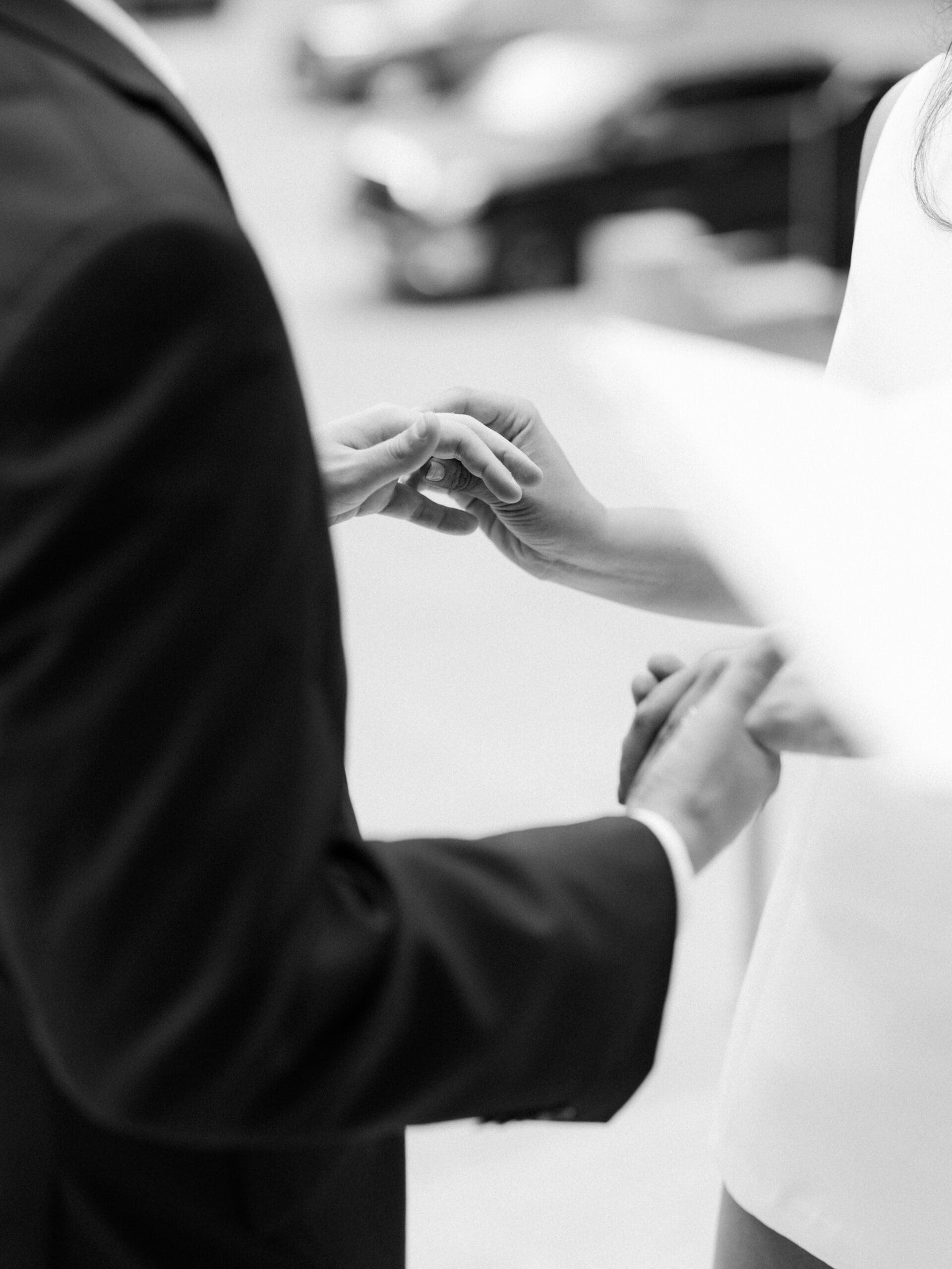 Close-up of a groom sliding a ring onto his bride's finger during their courthouse wedding in Houston
