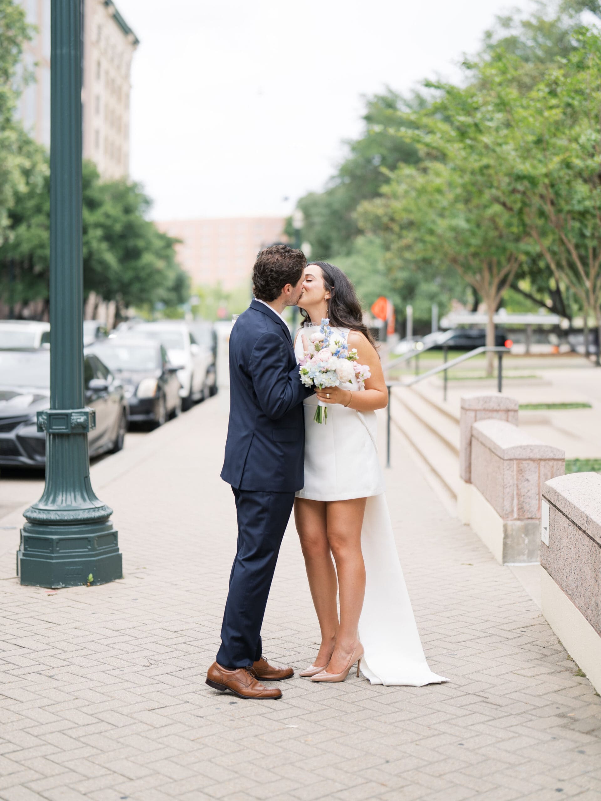 Bride and groom sharing a kiss on a downtown Houston sidewalk after their courthouse wedding in Houston
