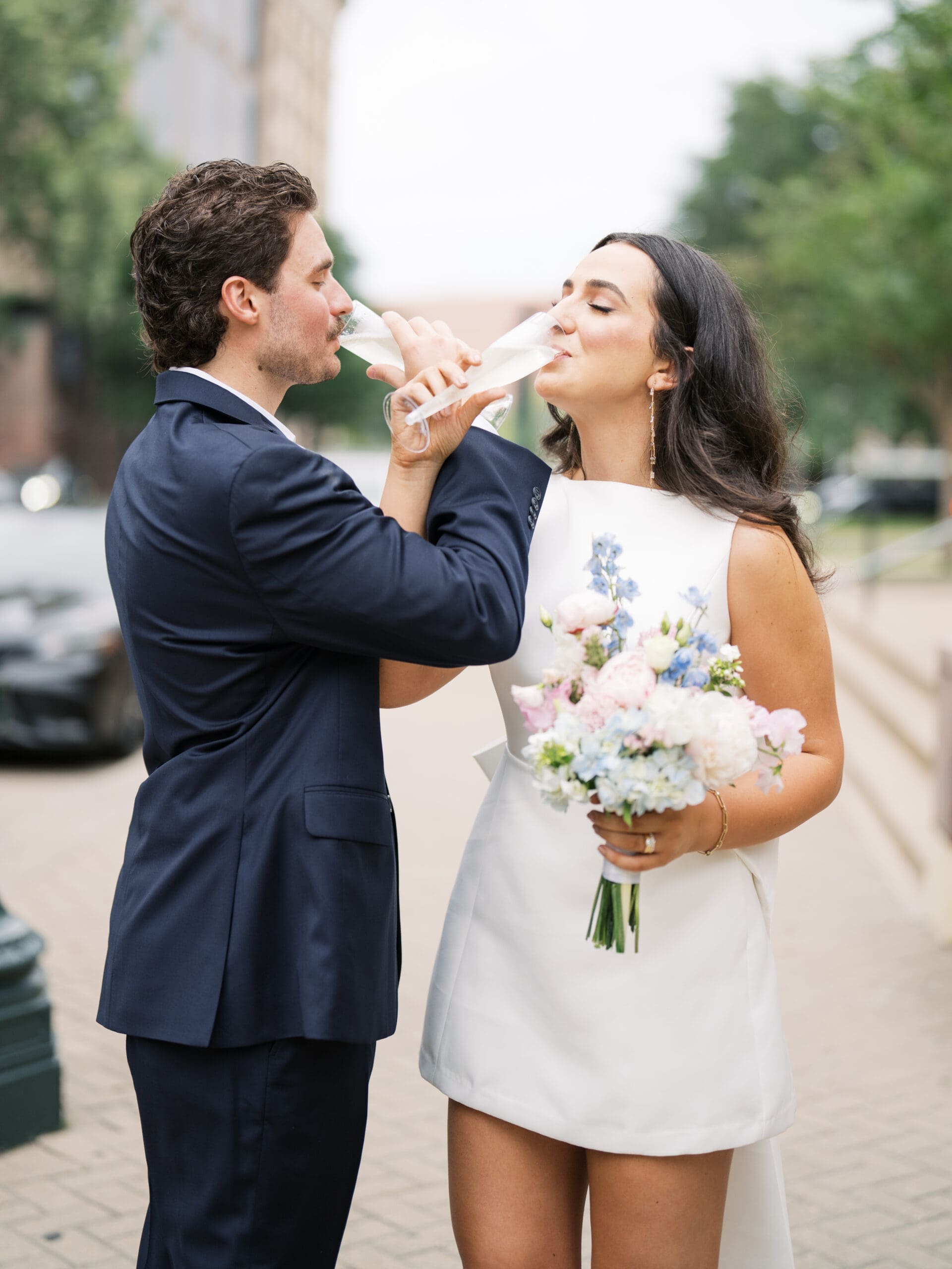Bride and groom toasting with champagne glasses outdoors after the ceremony

