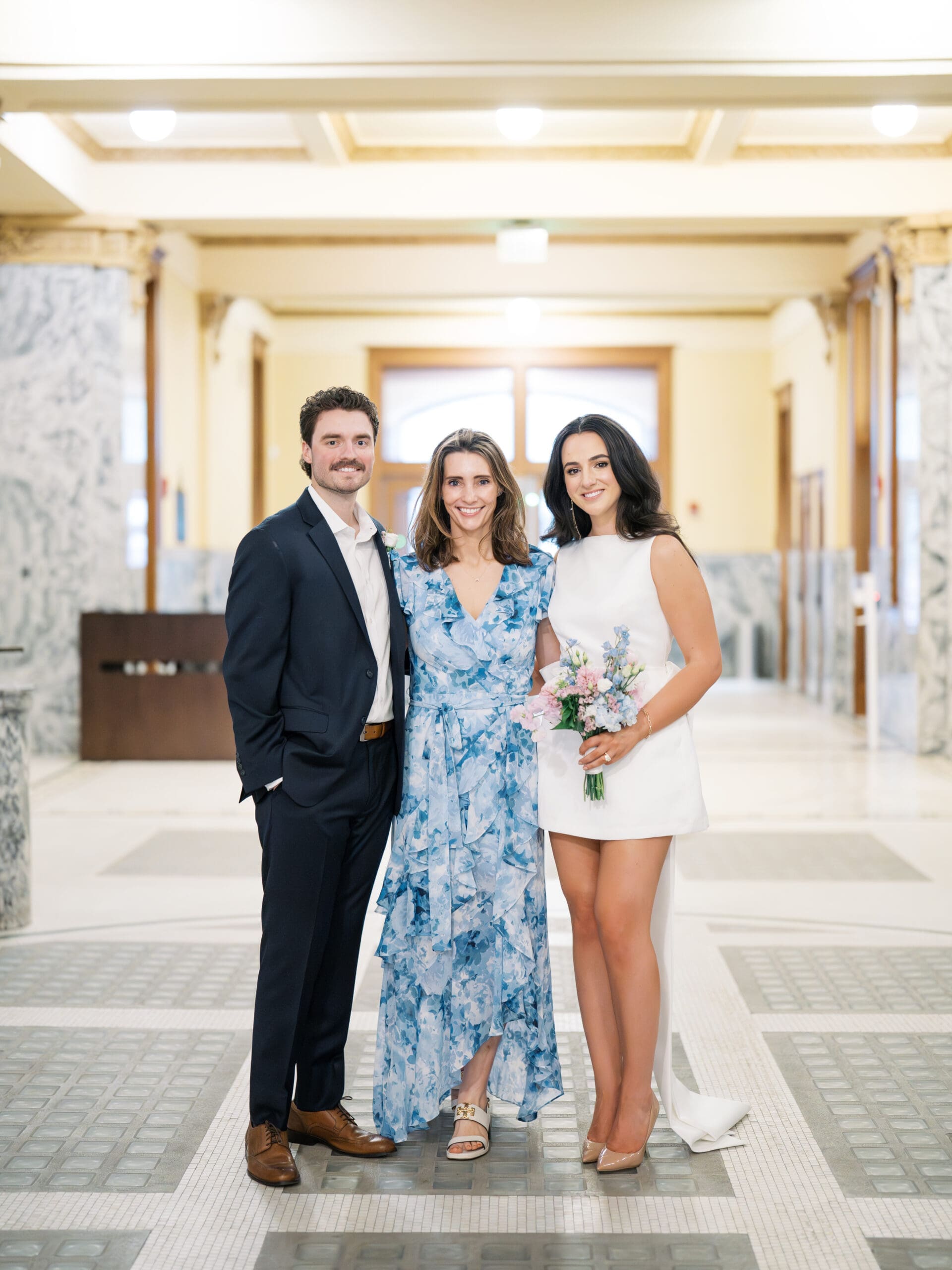 Bride hugging groom from behind on granite steps, both laughing