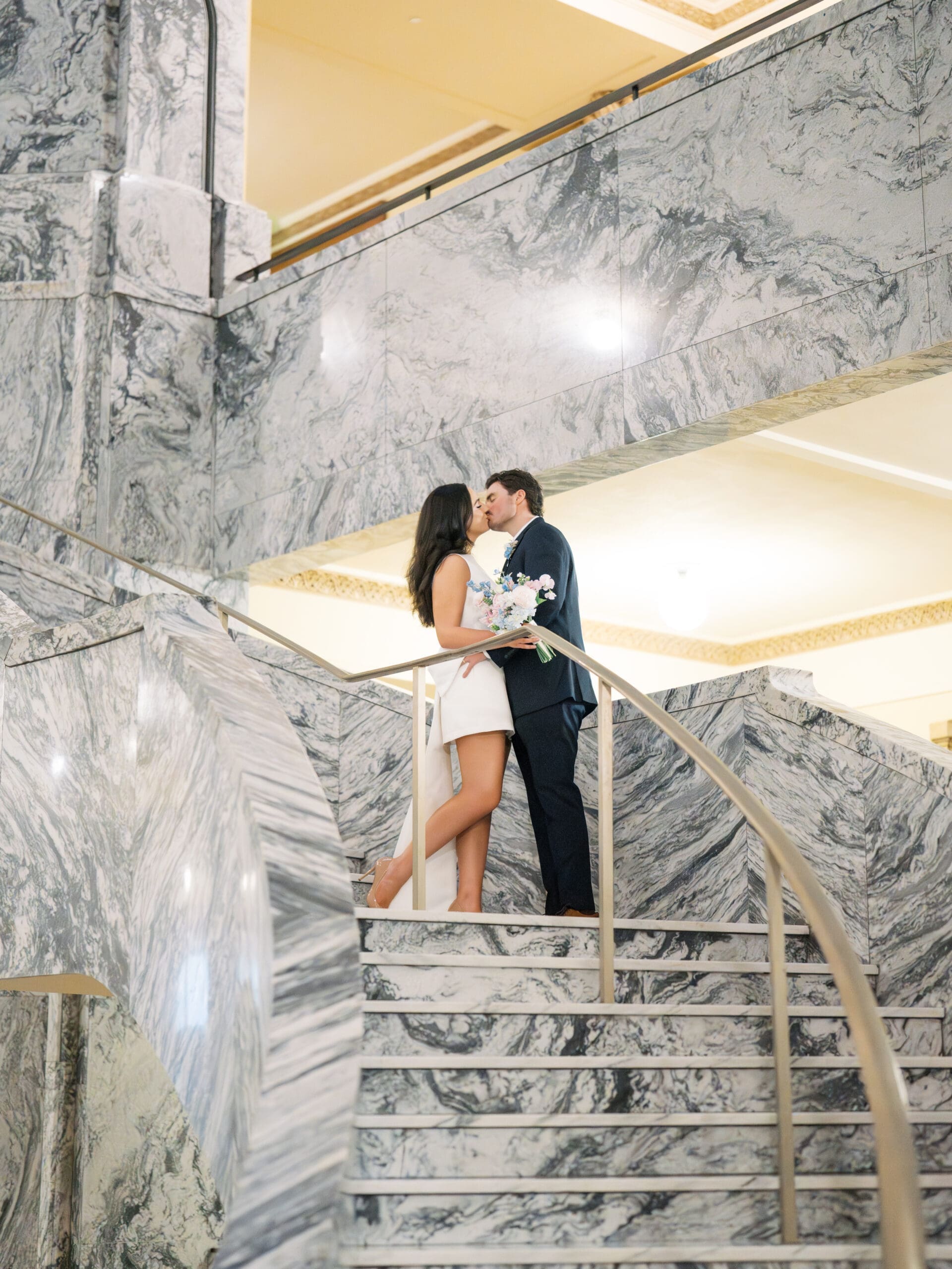Couple sharing a kiss on the marble staircase inside the Harris County courthouse
