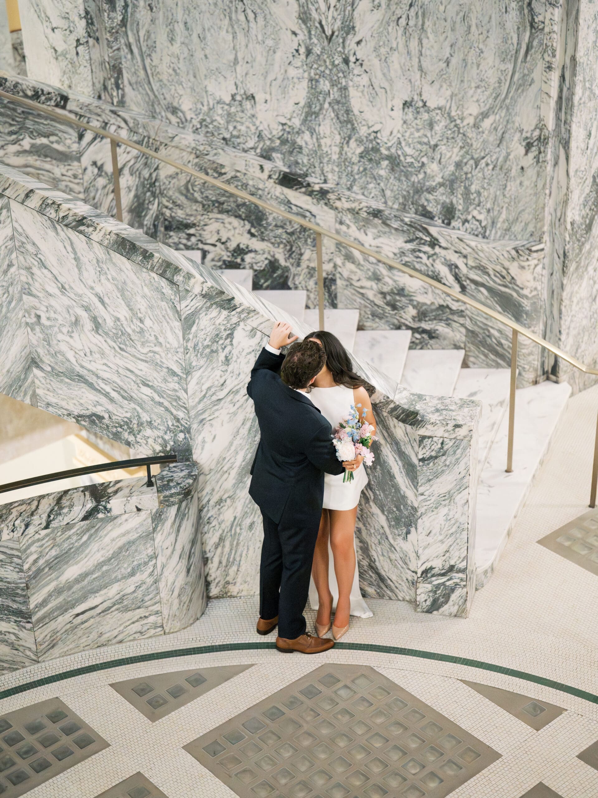 Couple kissing beside a dramatic marble staircase during their courthouse wedding in Houston
