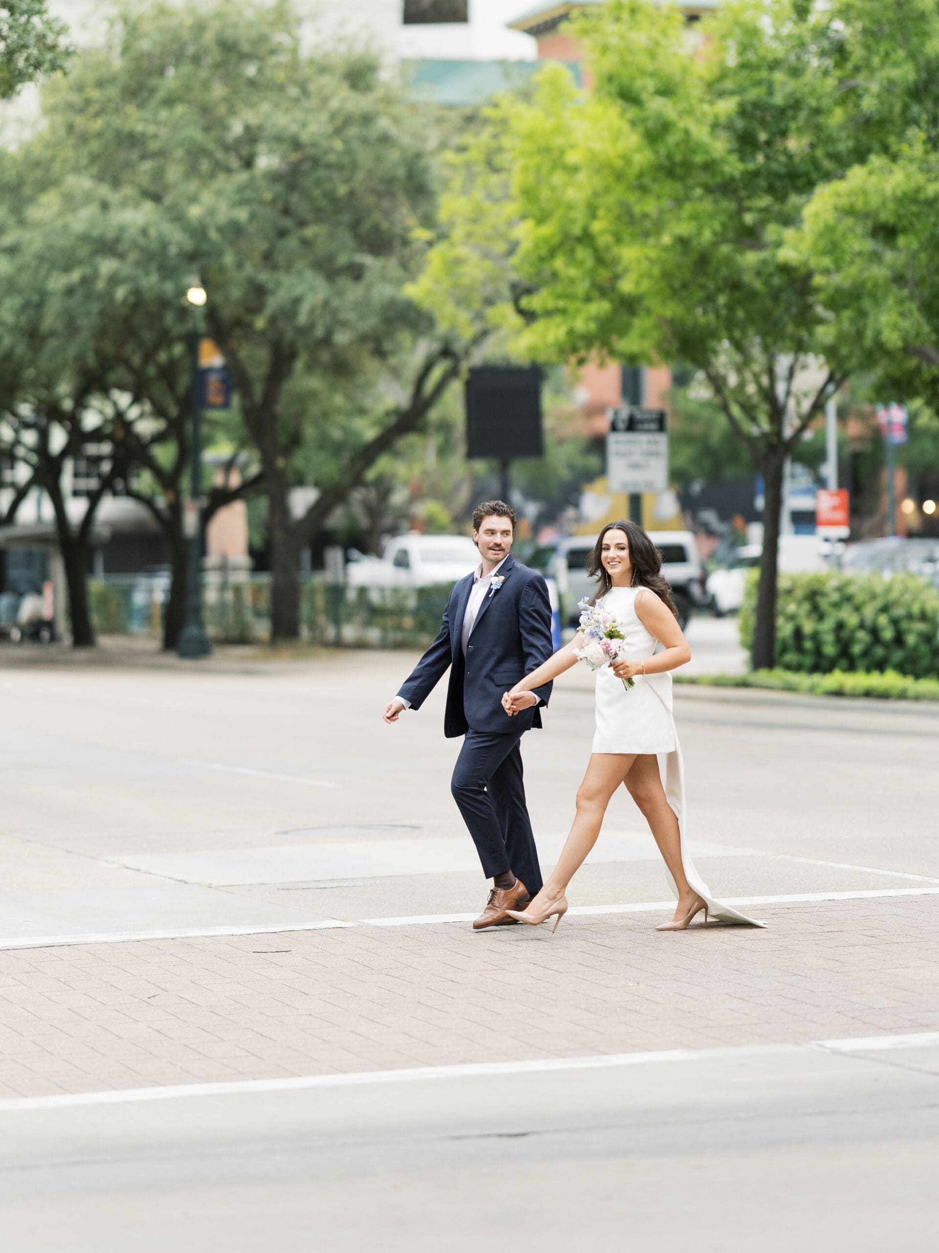 Couple walking hand in hand across a downtown Houston intersection during their courthouse wedding
