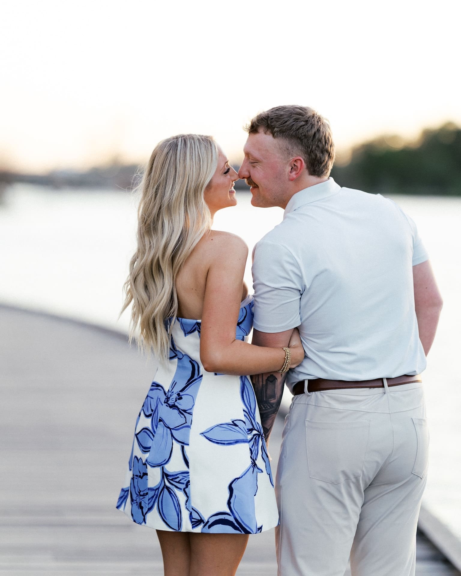 Couple laughing together on a dock at sunset after getting engaged in Houston

