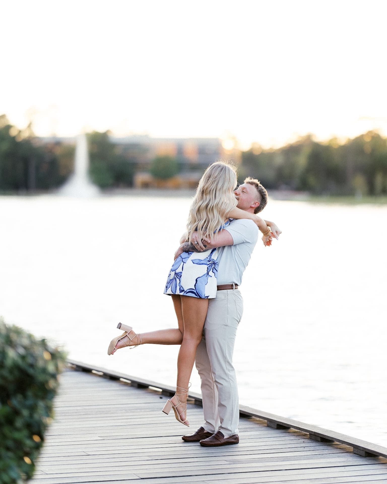 Man lifting his fiancée on a boardwalk at golden hour after she said yes to his proposal in Houston
