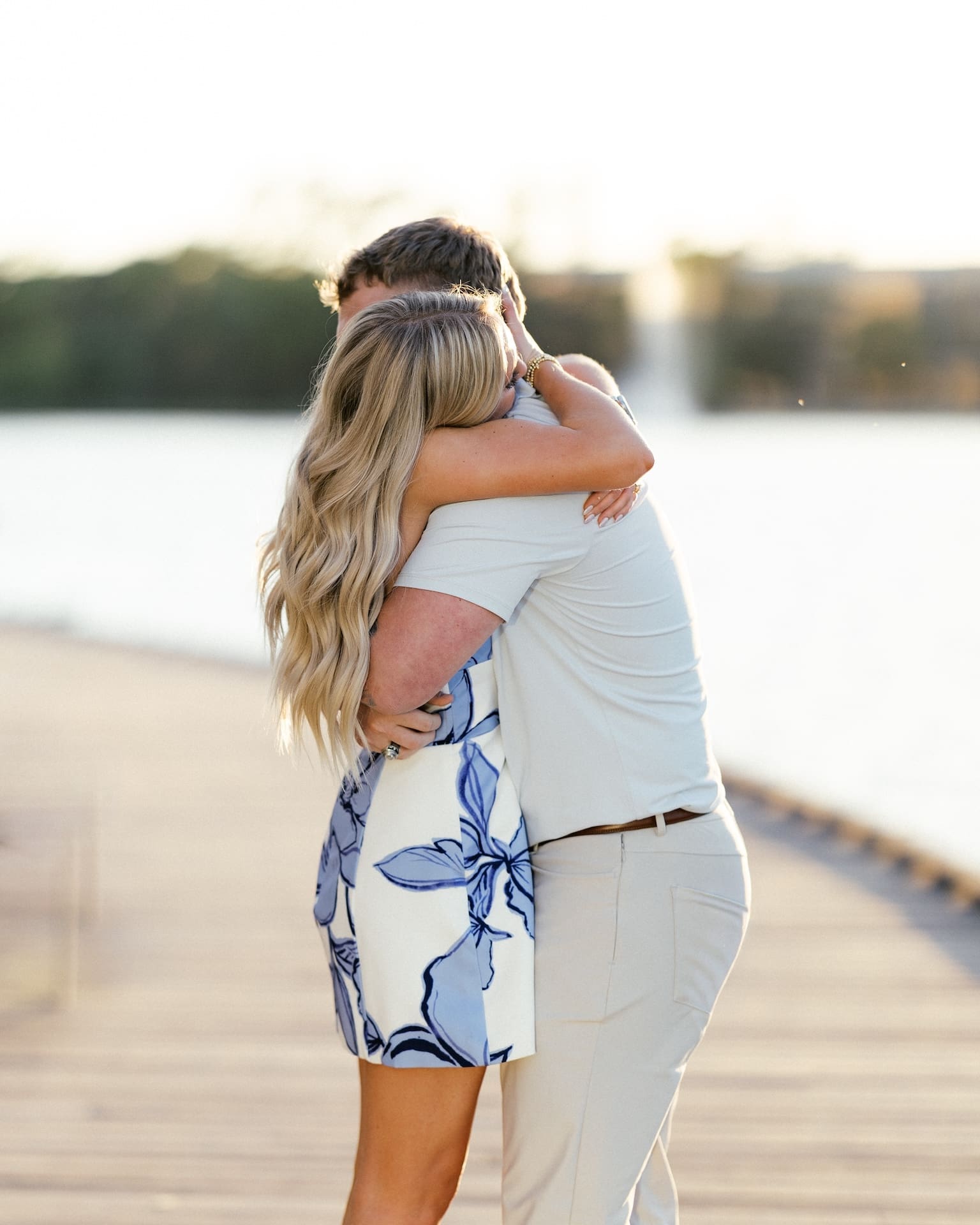 Woman hugging her now fiance tightly after saying yes during a surprise waterfront proposal
