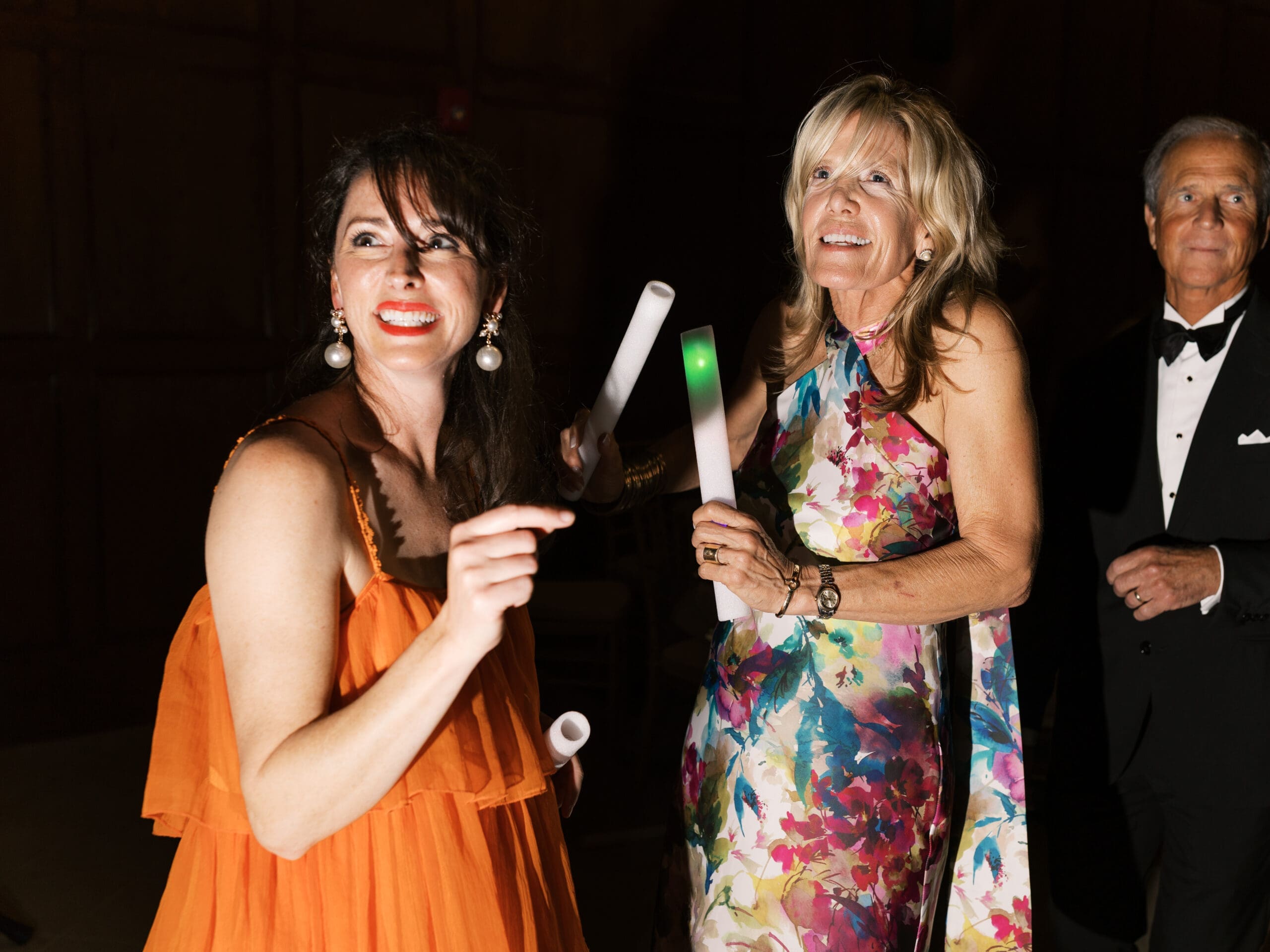 Guests holding glow sticks and cheering with excitement during the sparkler send-off at The Lanier Theological Library wedding reception.

