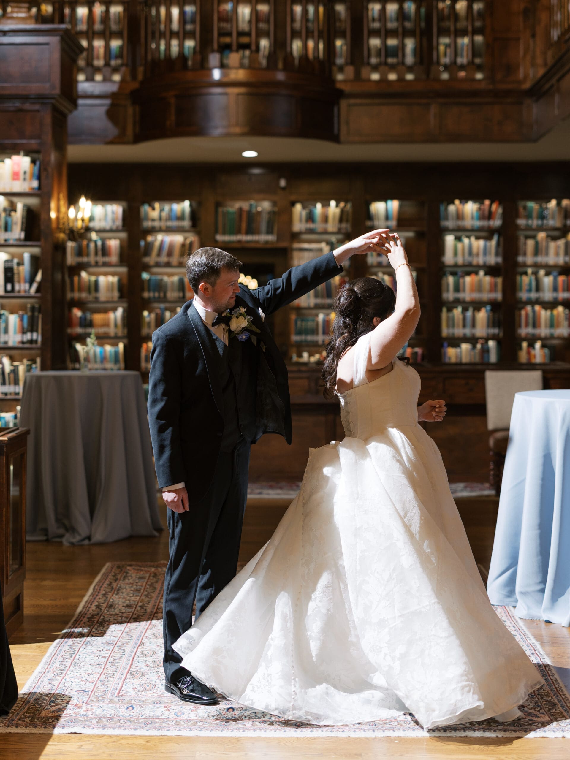 Bride and groom sharing their first dance in the grand library reception hall of The Lanier Theological Library, surrounded by floor-to-ceiling bookshelves.
