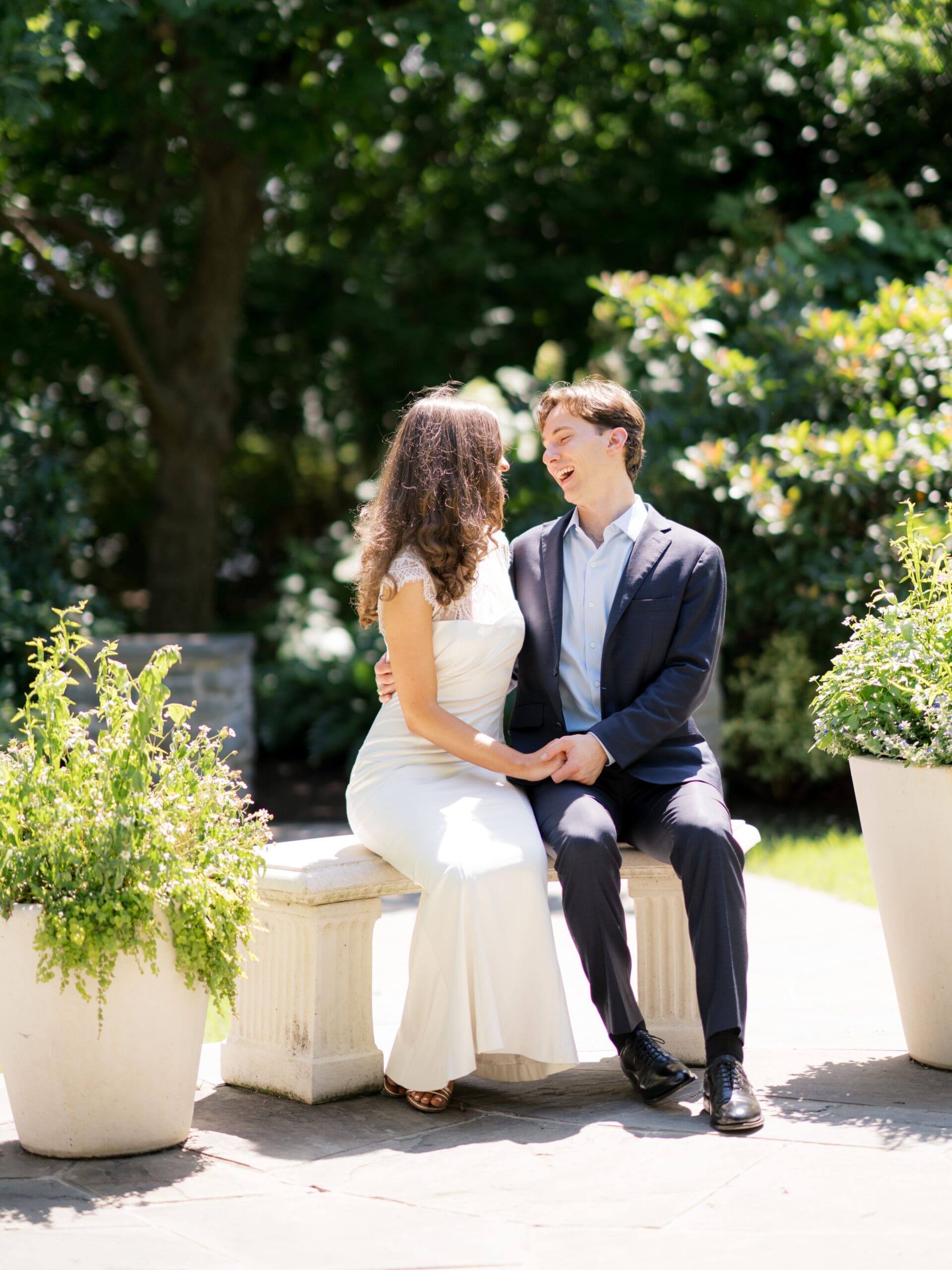 Fall engagement photos of a couple laughing together while sitting on a garden bench.