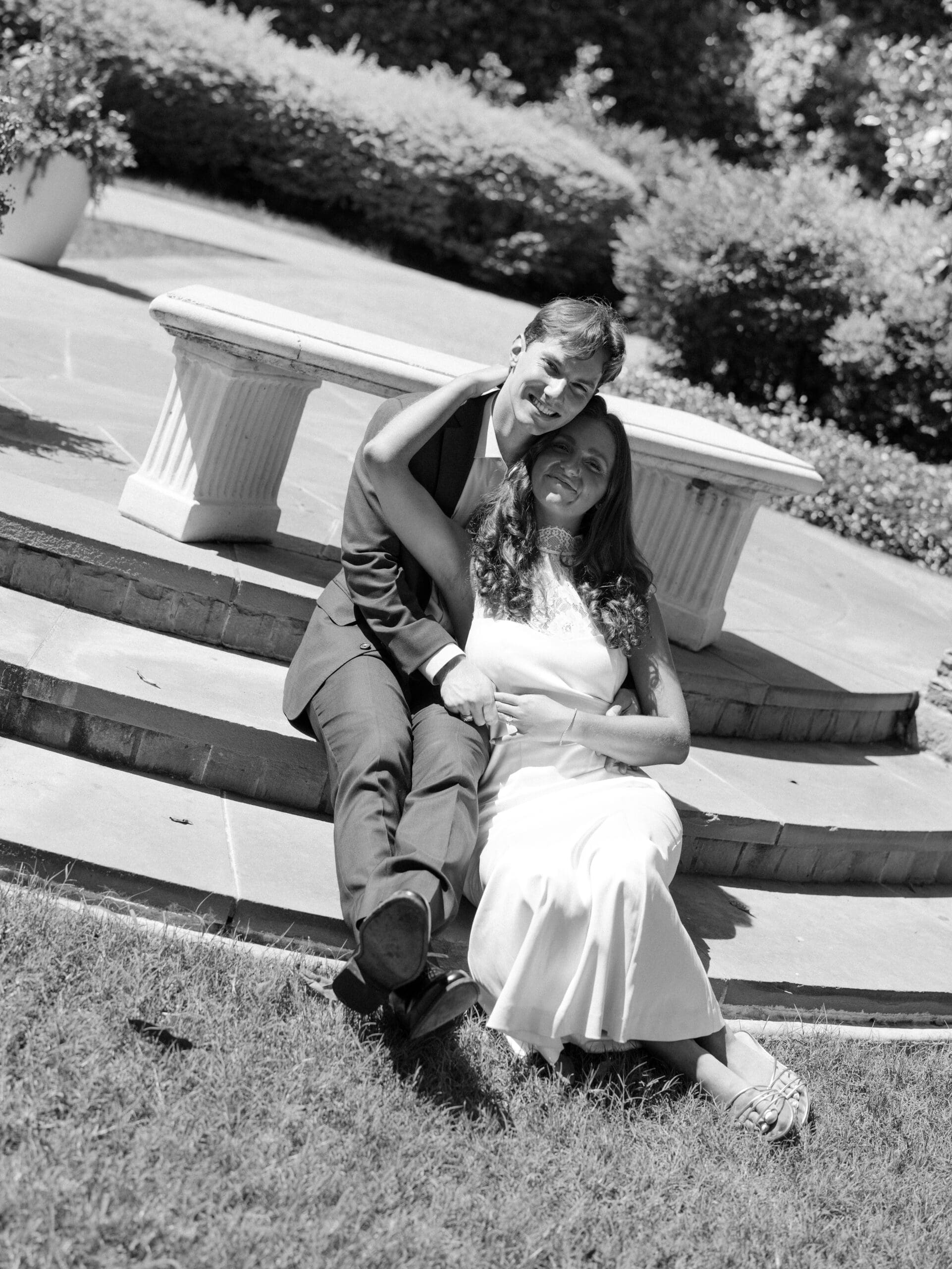 Fall engagement photos of a couple laughing together on stone garden steps in black and white.