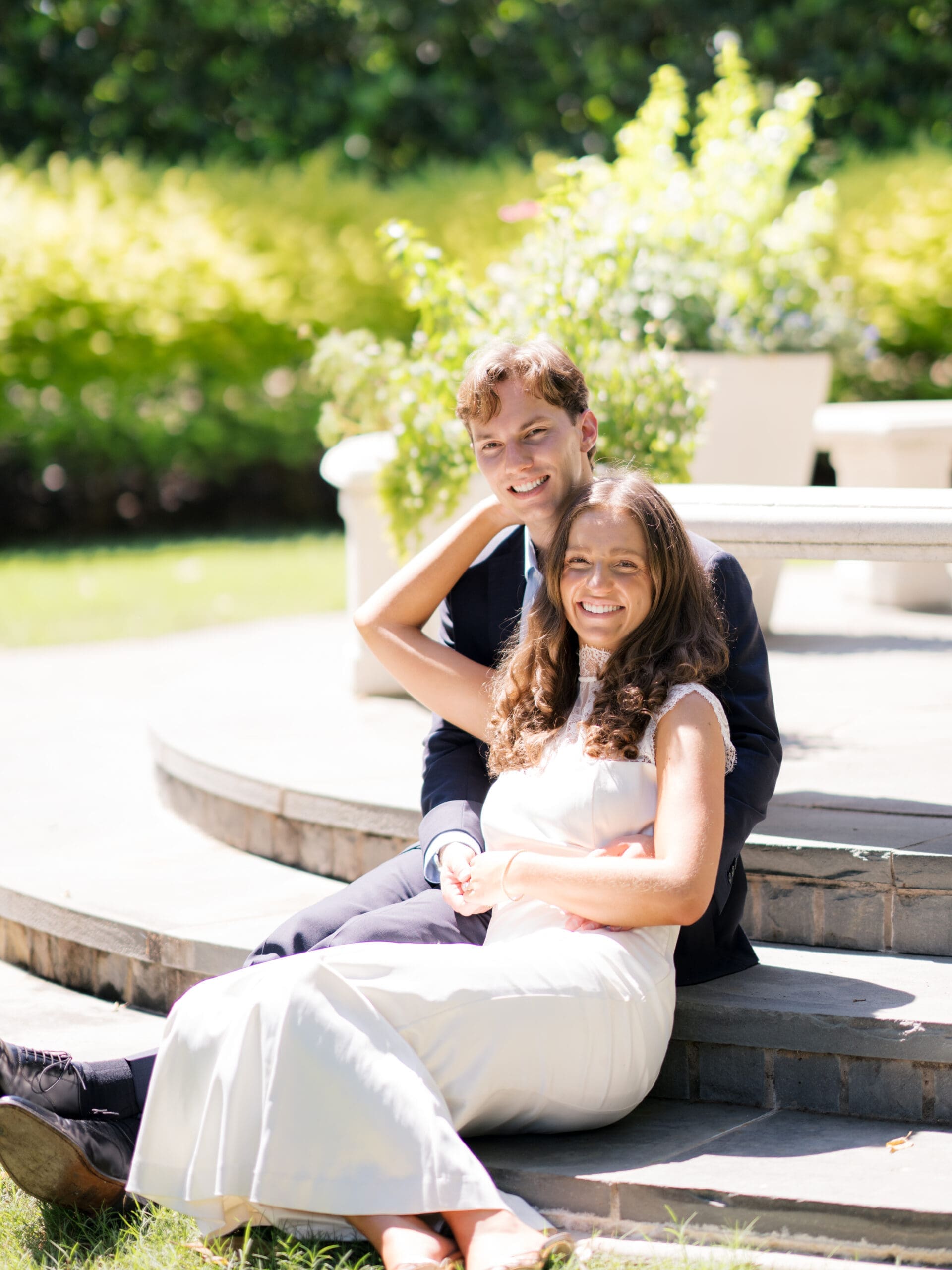 Couple smiling and embracing while sitting together on garden steps.
