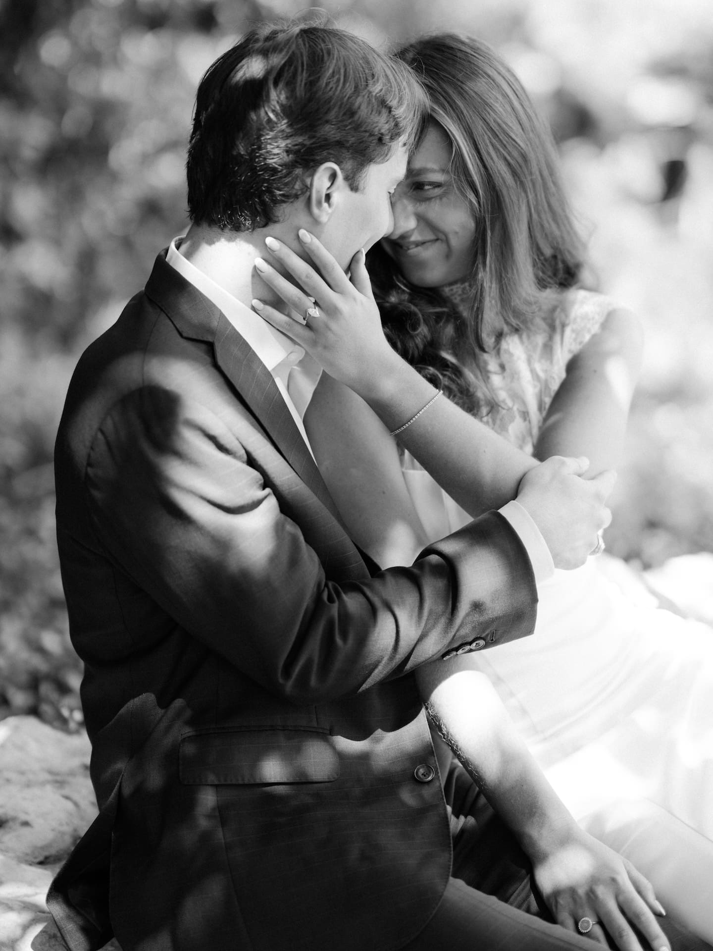 Black and white close-up of a couple embracing tenderly with foreheads nearly touching.