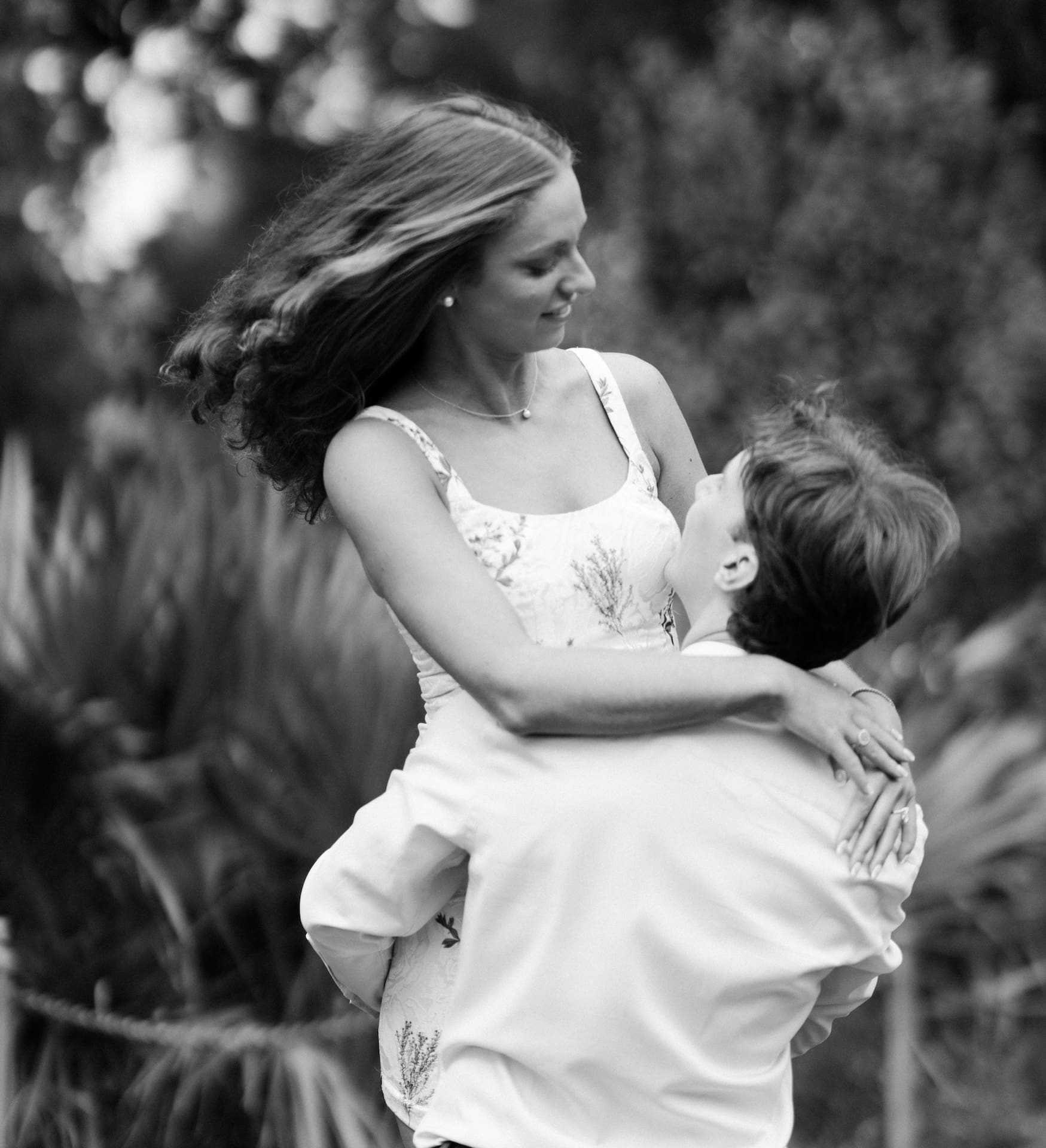 Black and white photo of a groom joyfully lifting his bride-to-be off the ground.