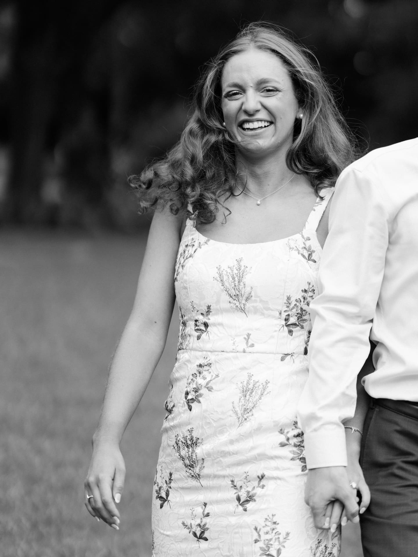 Black and white close-up of a bride-to-be laughing candidly in a floral dress.