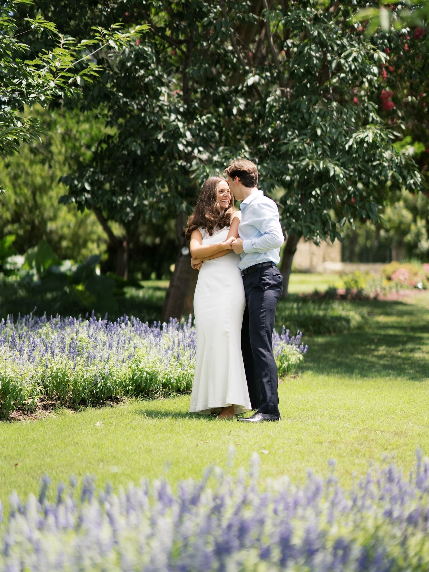 Couple embracing tenderly beside a bed of purple lavender flowers.