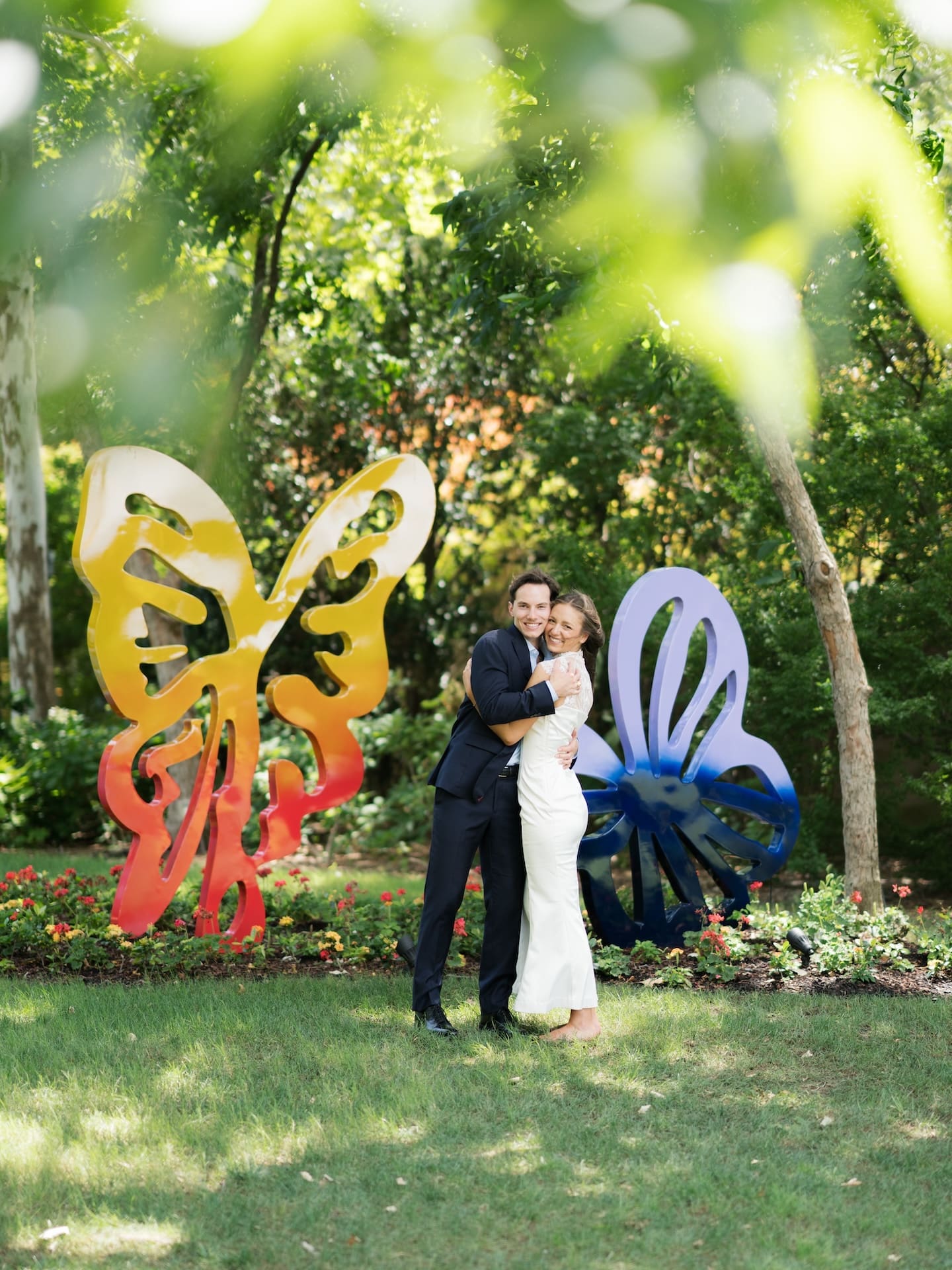 Fall engagement photos of a couple hugging warmly between vibrant yellow and blue butterfly art pieces.